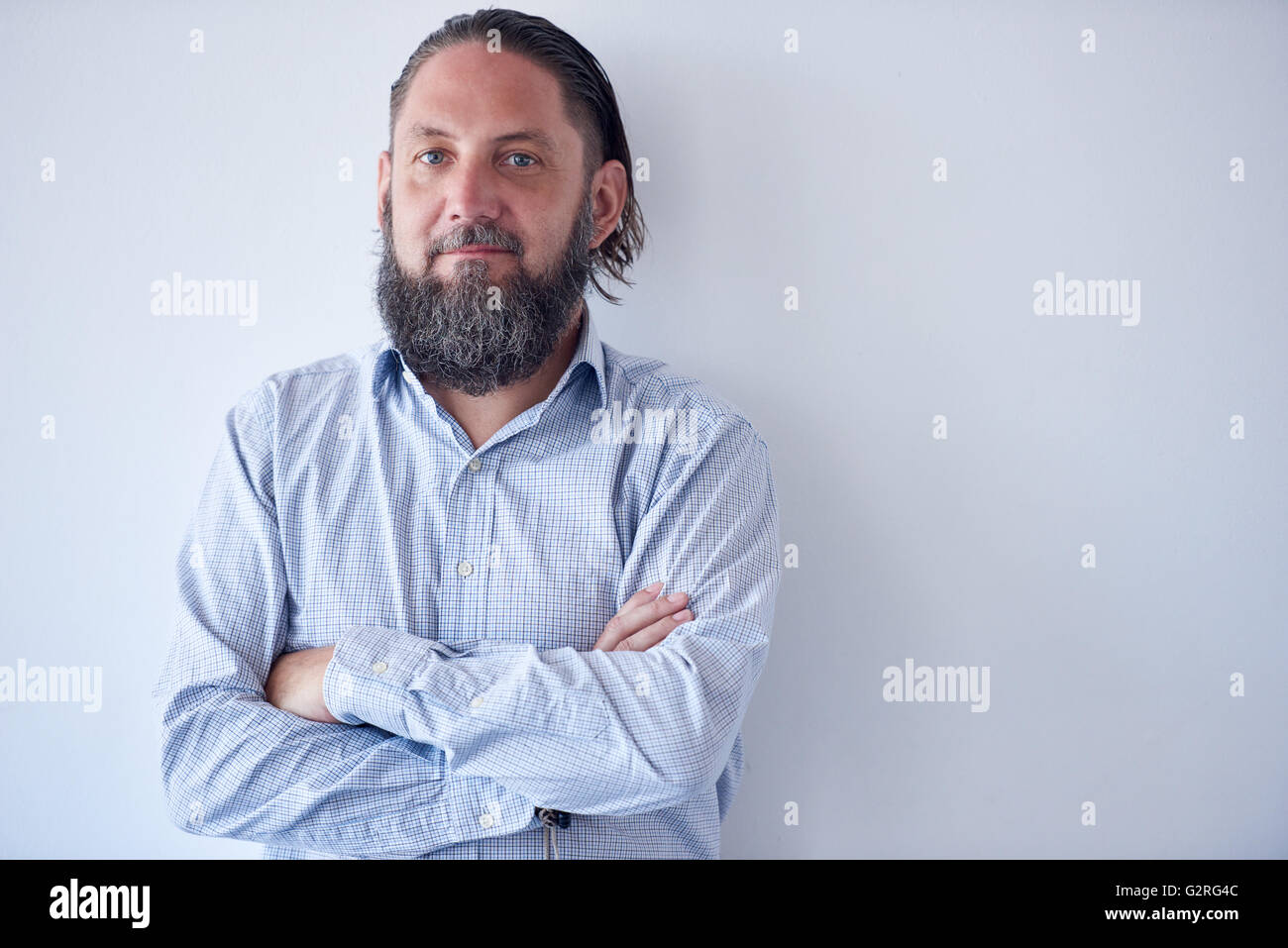 Portrait of Mature man with arms crossed agianst white wall Stock Photo ...