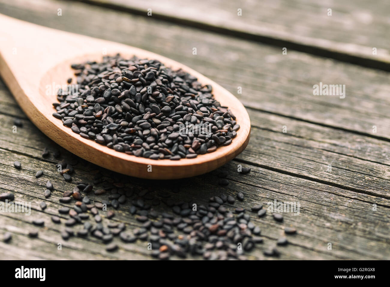 Black sesame seeds. Healthy sesame seeds in spoon on wooden table Stock