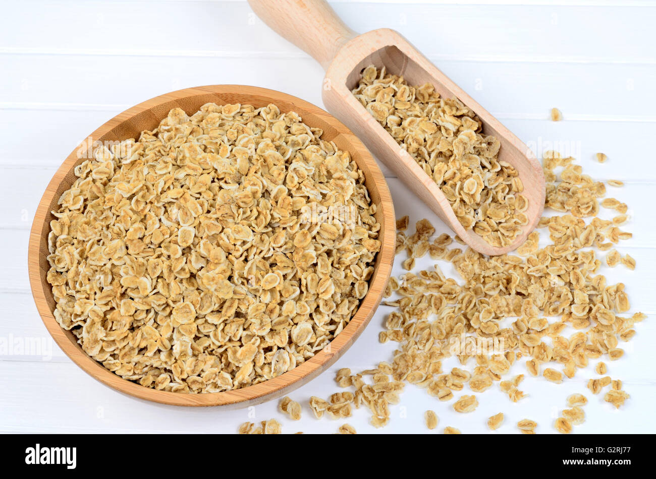 Bowl with oats and scoop on wooden table Stock Photo