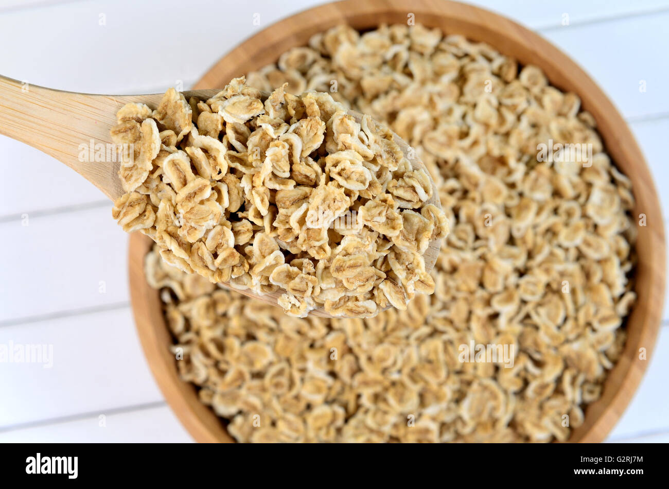 Wooden spoon with oats on white table Stock Photo