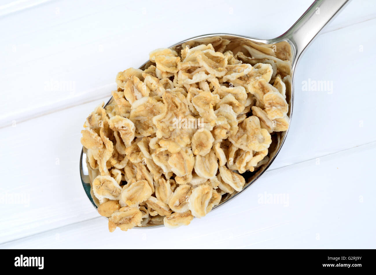 Organic oatmeal in silver spoon on white wooden table Stock Photo