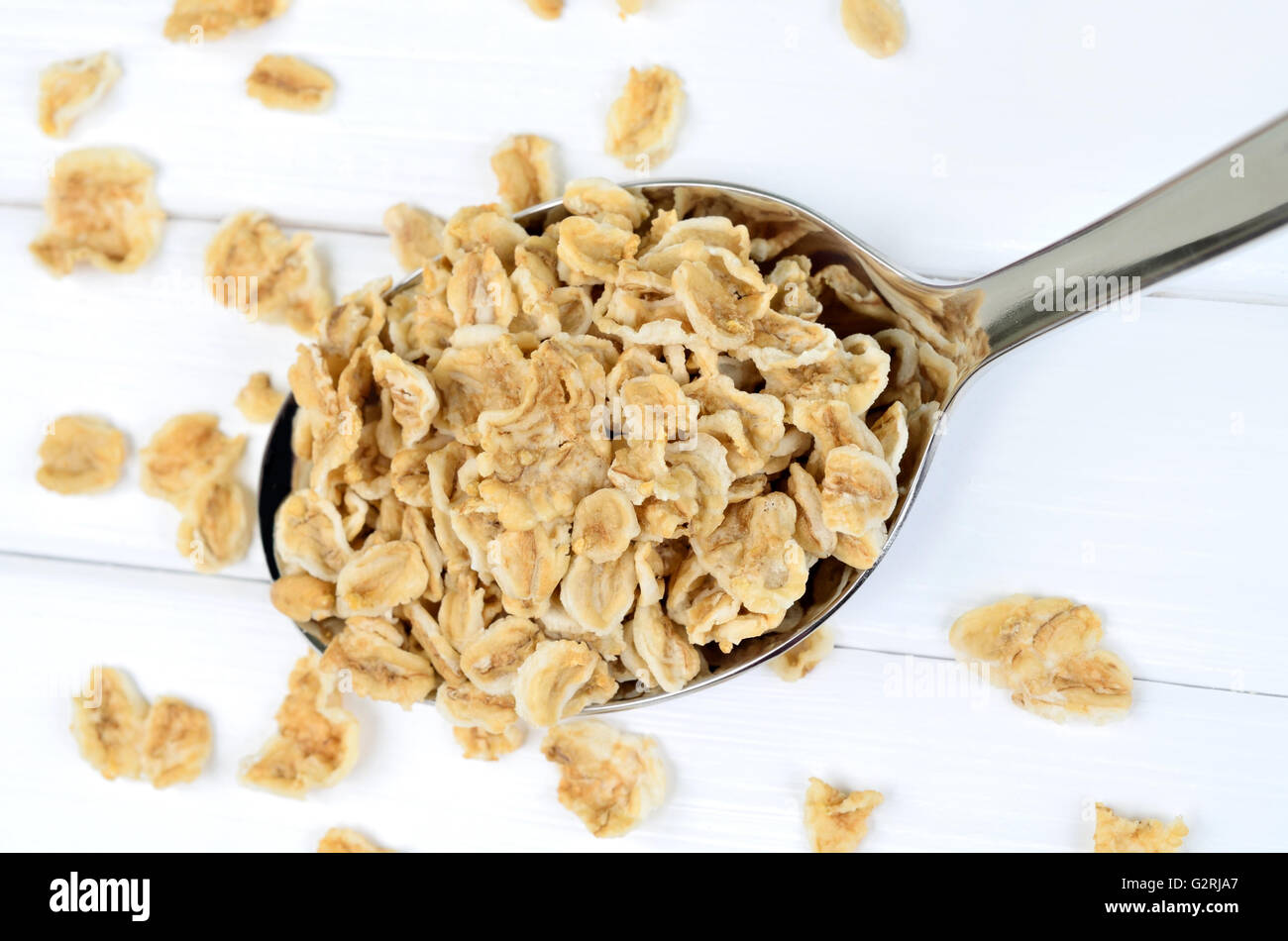 Oat flakes in silver spoon on white wooden table Stock Photo