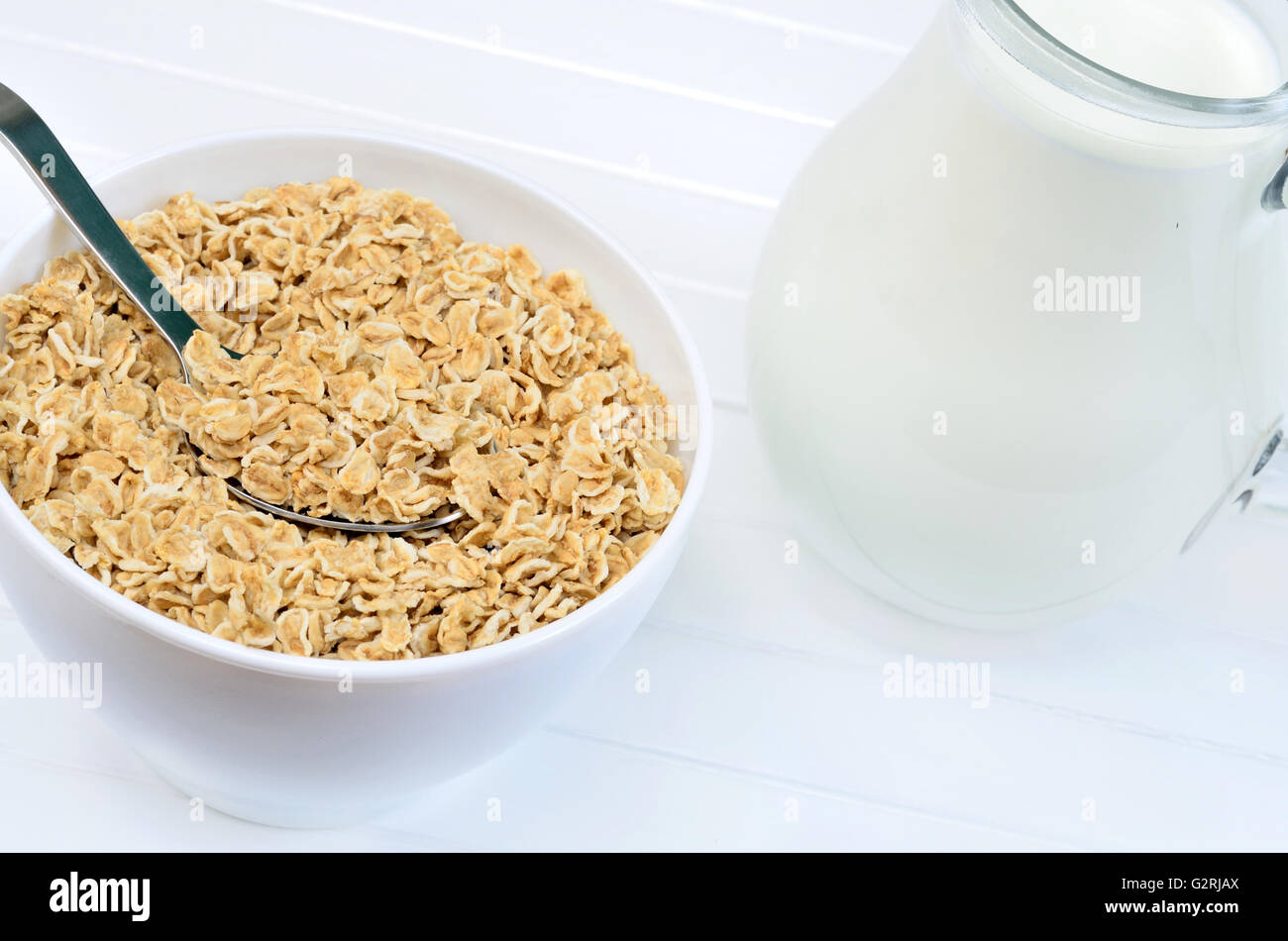 Oat flakes in a white bowl with milk on wooden table Stock Photo