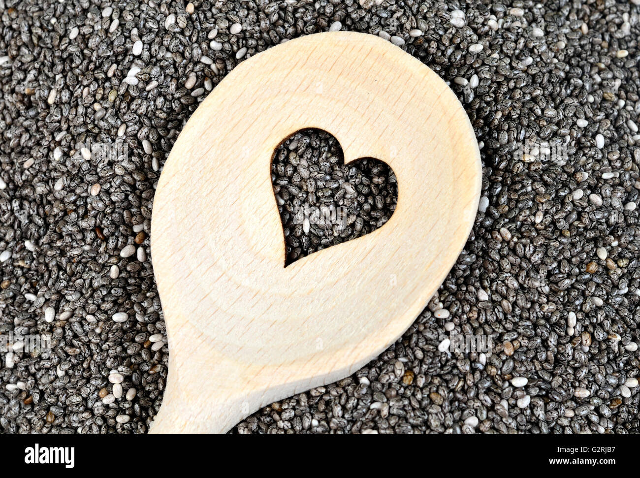 Wooden spoon with heart shape cutted on chia seeds on background Stock Photo