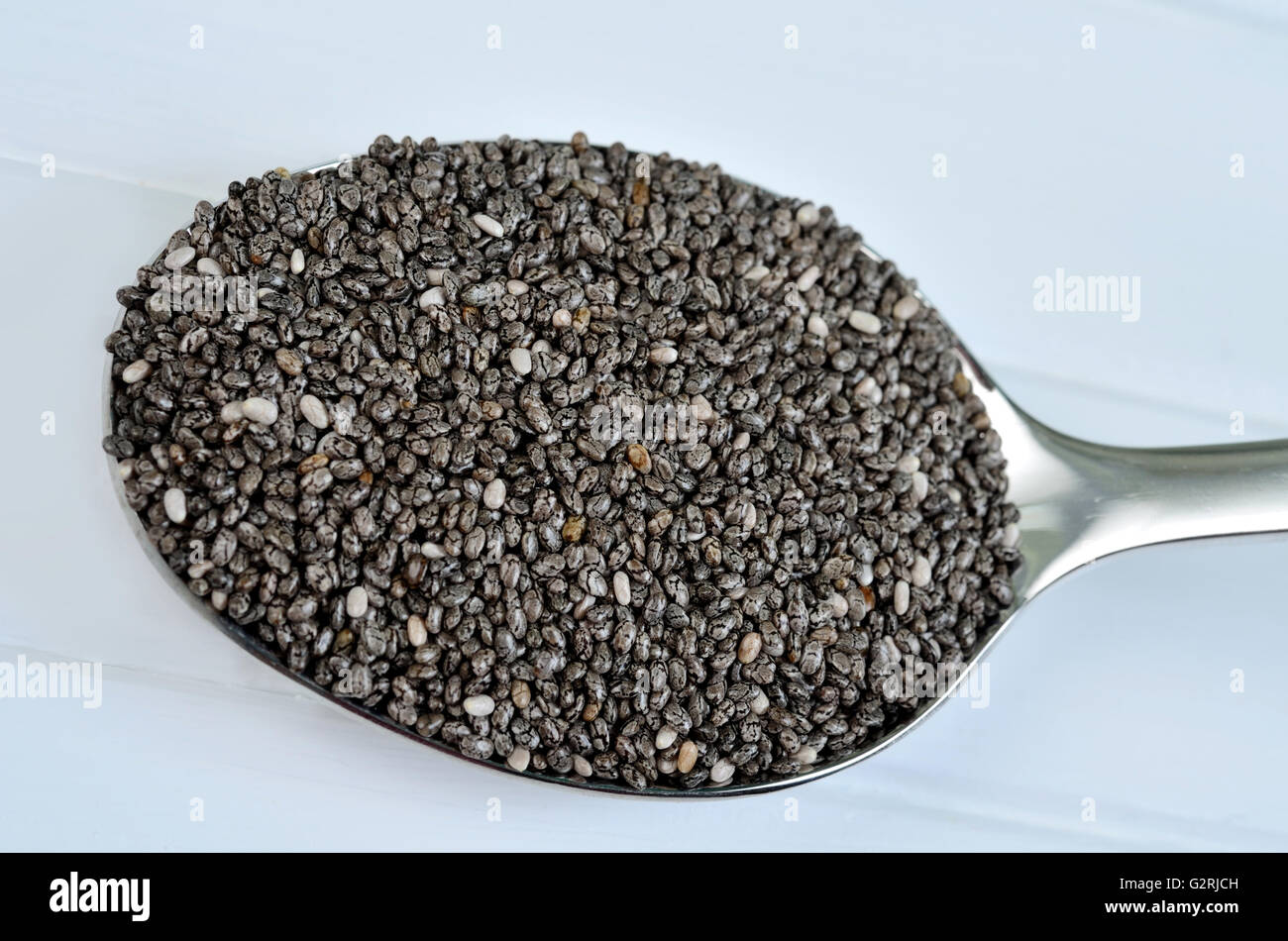 Healthy chia seeds in silver spoon on wooden table Stock Photo