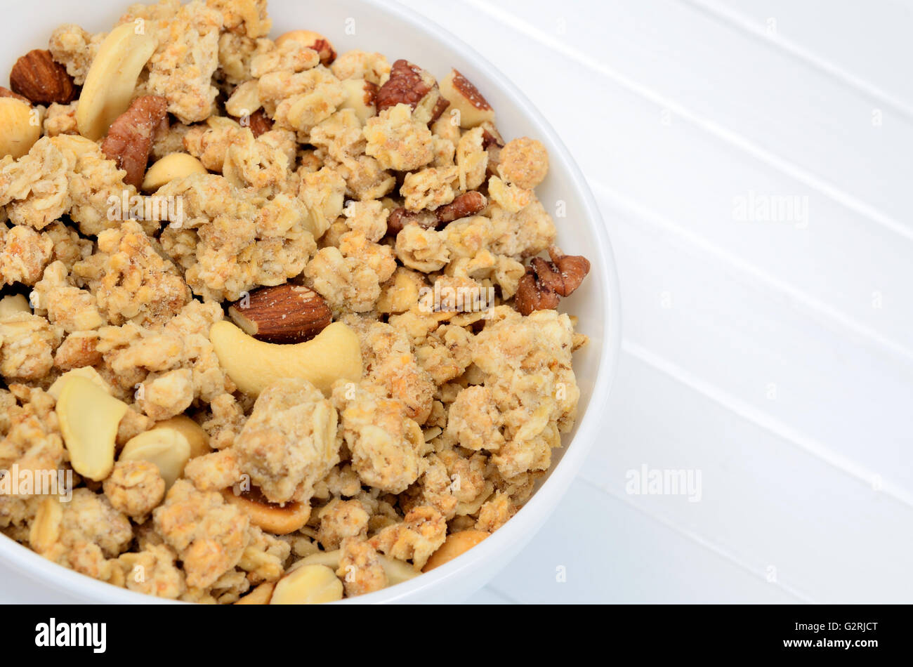 Muesli in bowl on white wooden table Stock Photo
