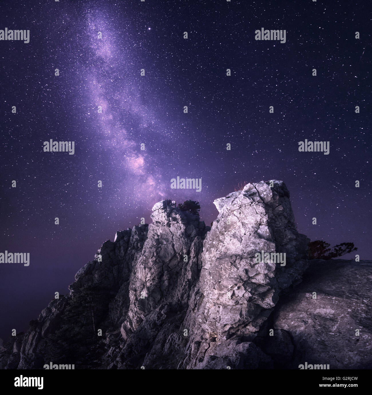 Beautiful night landscape with rocks and starry sky on the background of purple Milky Way, Magic Universe, mountains. Stock Photo