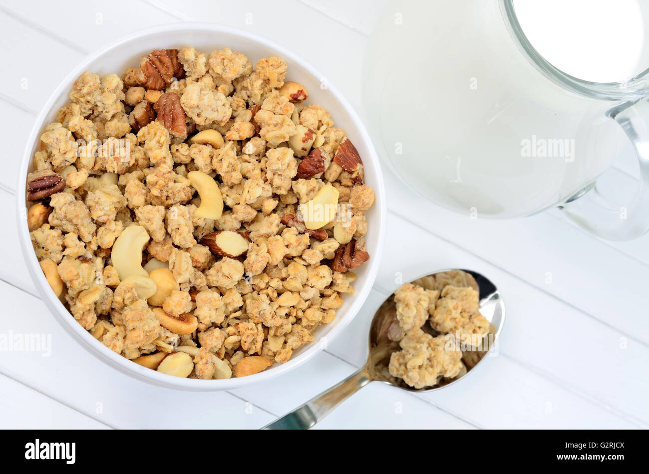 Healthy muesli in bowl with milk on white wooden table Stock Photo