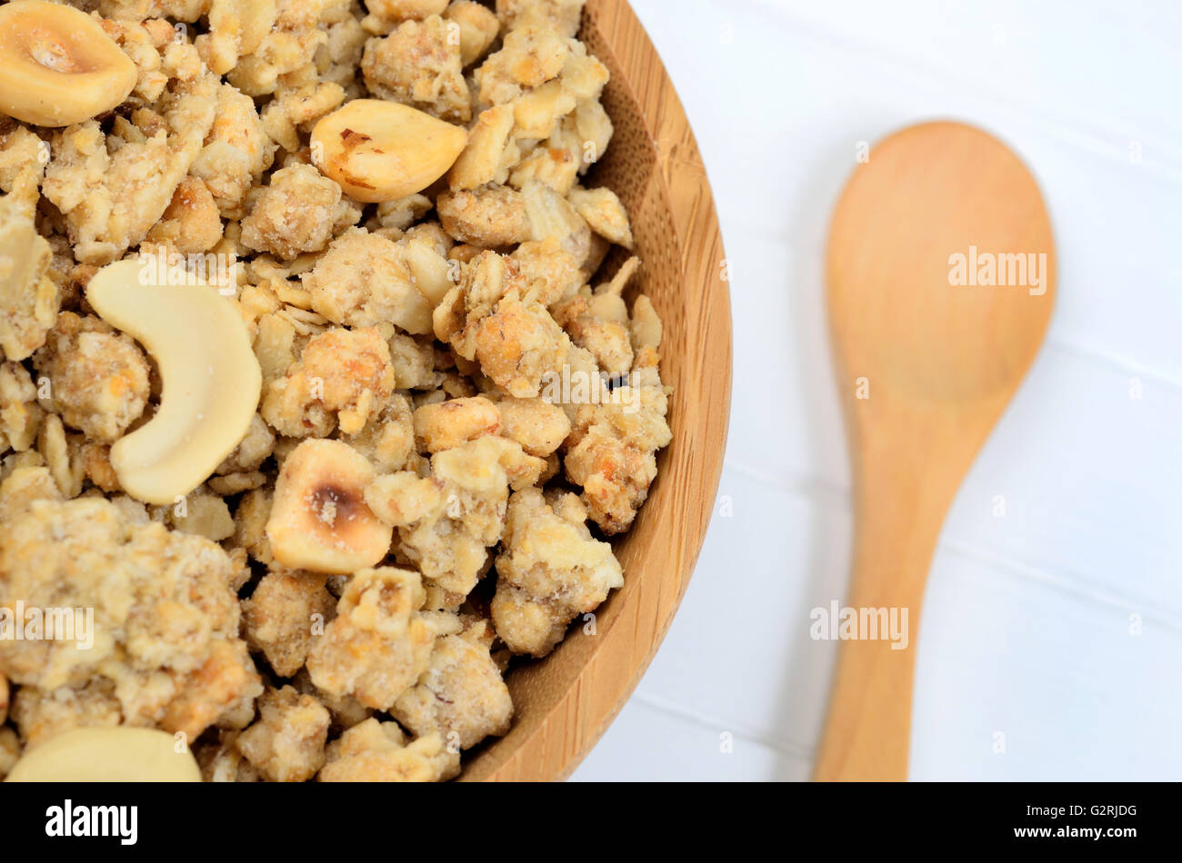 Muesli in bamboo bowl with wooden spoon on table Stock Photo