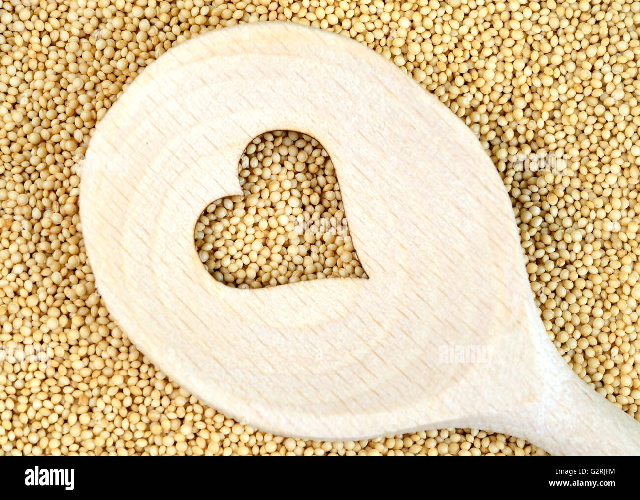 Wooden spoon with heart shape cutted on amaranth seeds Stock Photo