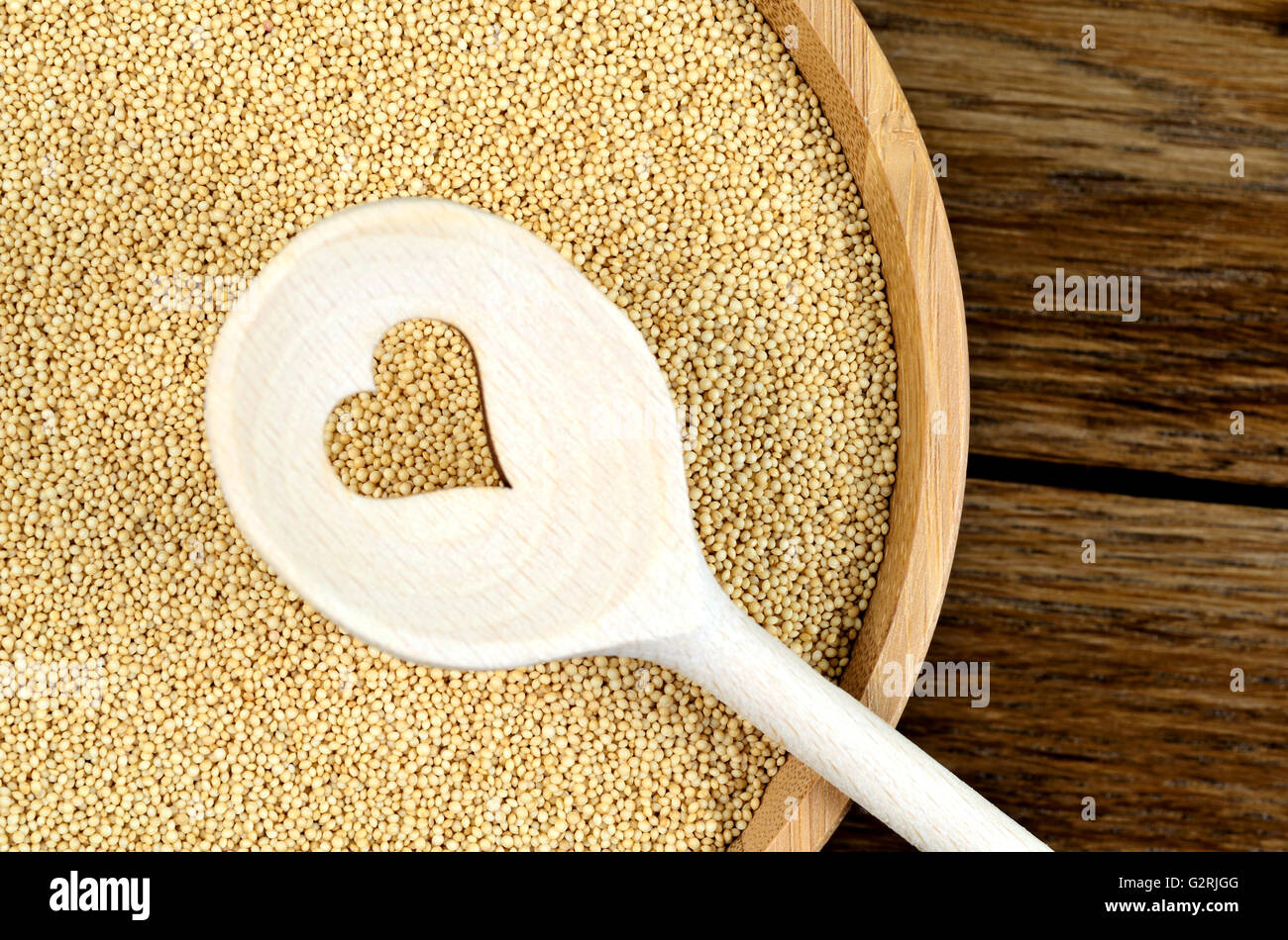 Amaranth seeds in a bamboo and wooden spoon with heart shape on table Stock Photo