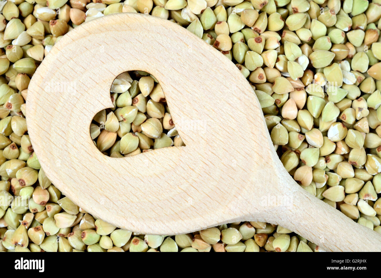 Wooden spoon with heart shape in a green buckwheat background Stock Photo