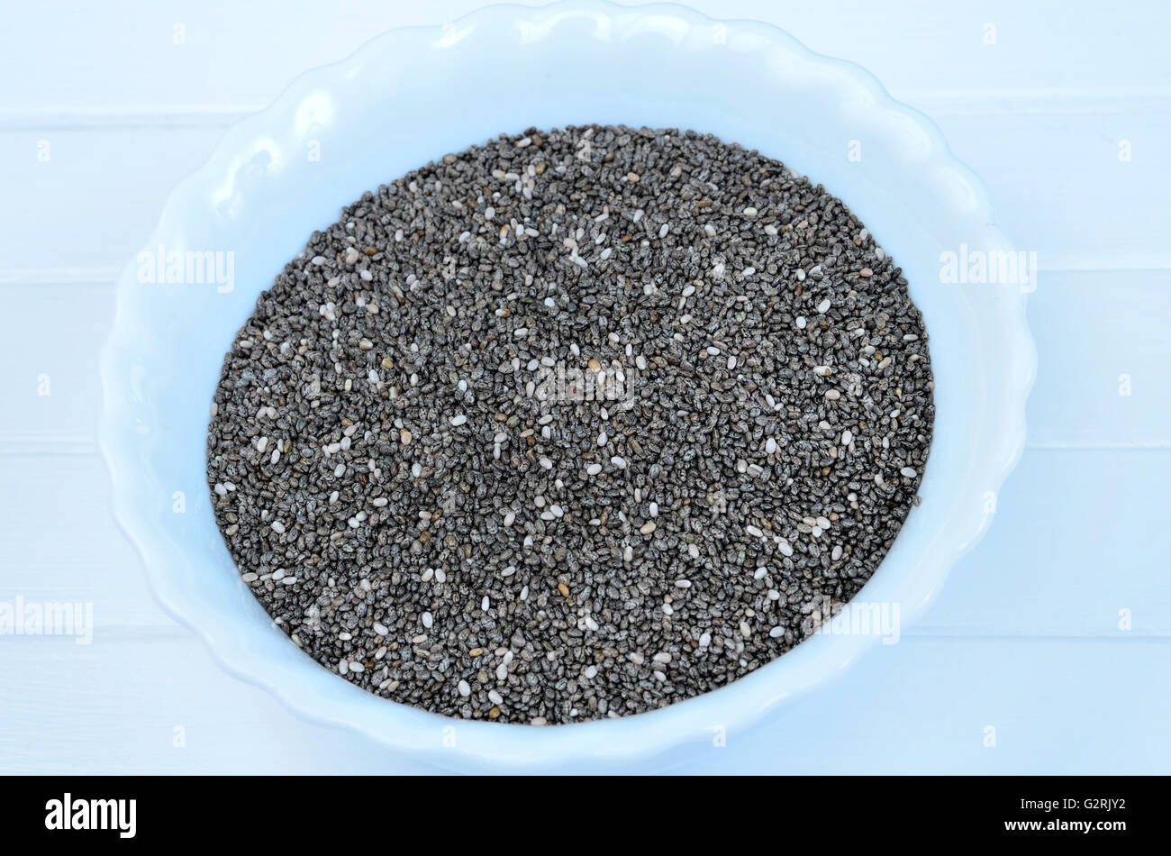 Chia seeds in a ceramic bowl on wooden table Stock Photo
