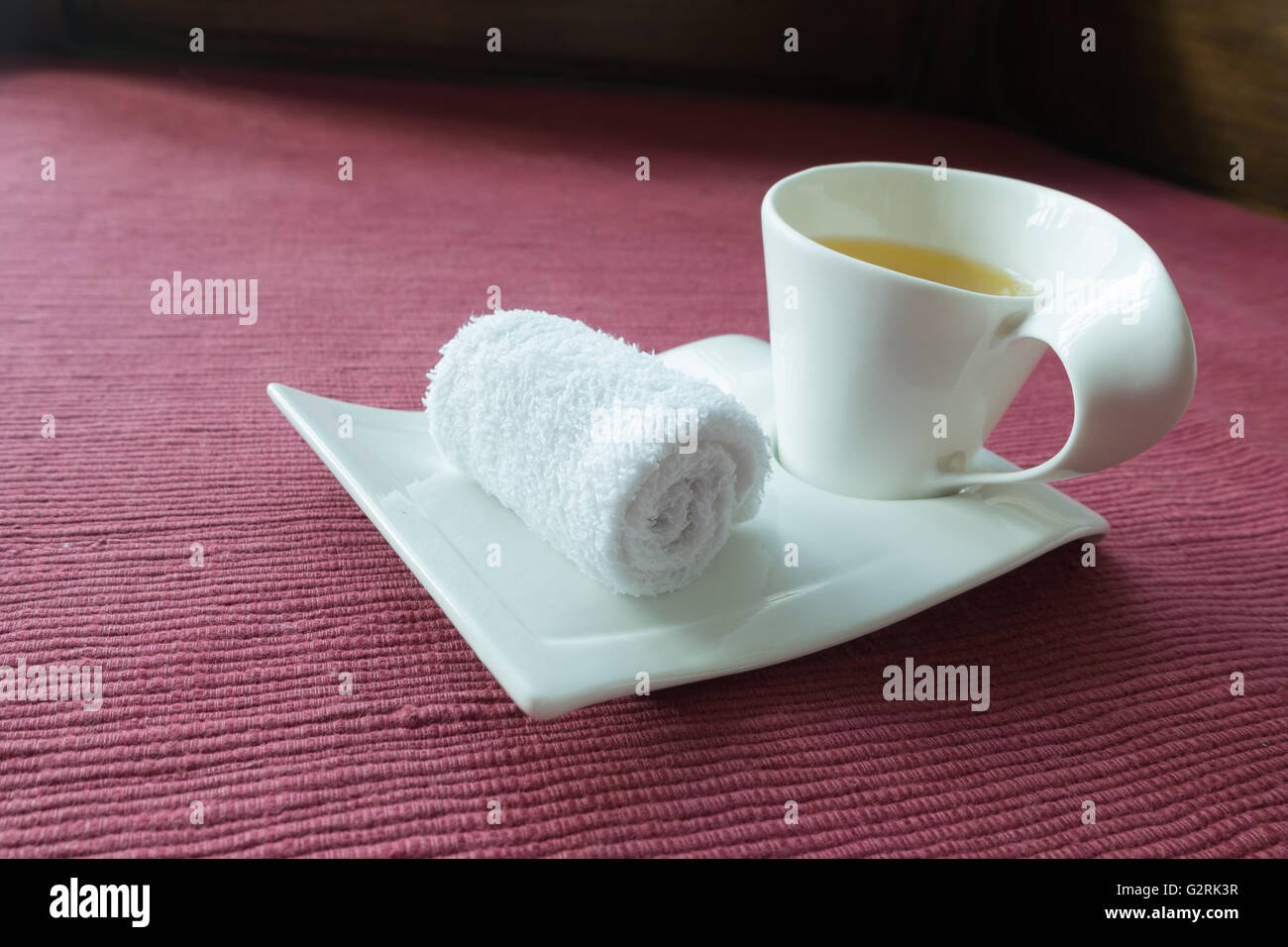 White scented rolled wet towel and hot herb tea to welcome guest, massage resort spa Stock Photo