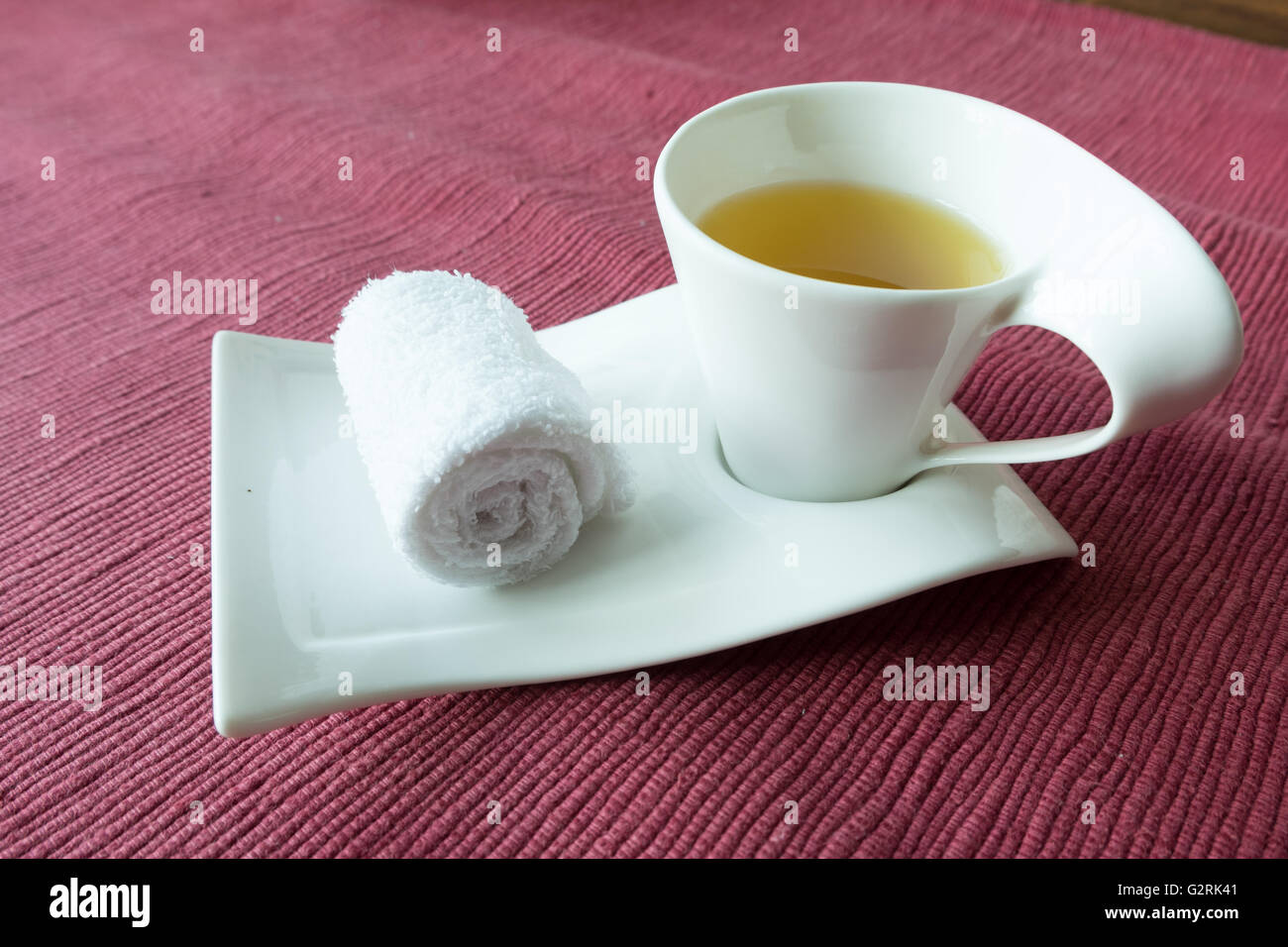 White scented rolled wet towel and hot herb tea to welcome guest, massage resort spa Stock Photo