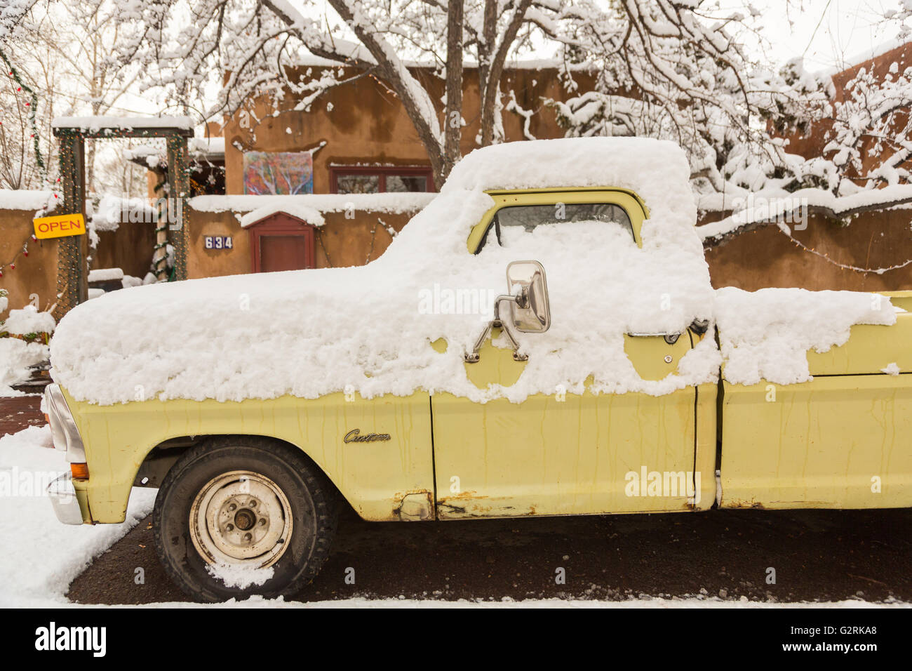 An old yellow pick up truck covered in snow on Canyon Road after a