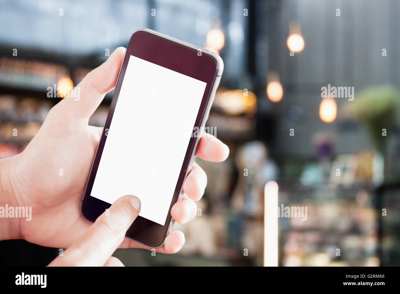 Hand holding blank screen mobile phone with blur coffee shop background Stock Photo