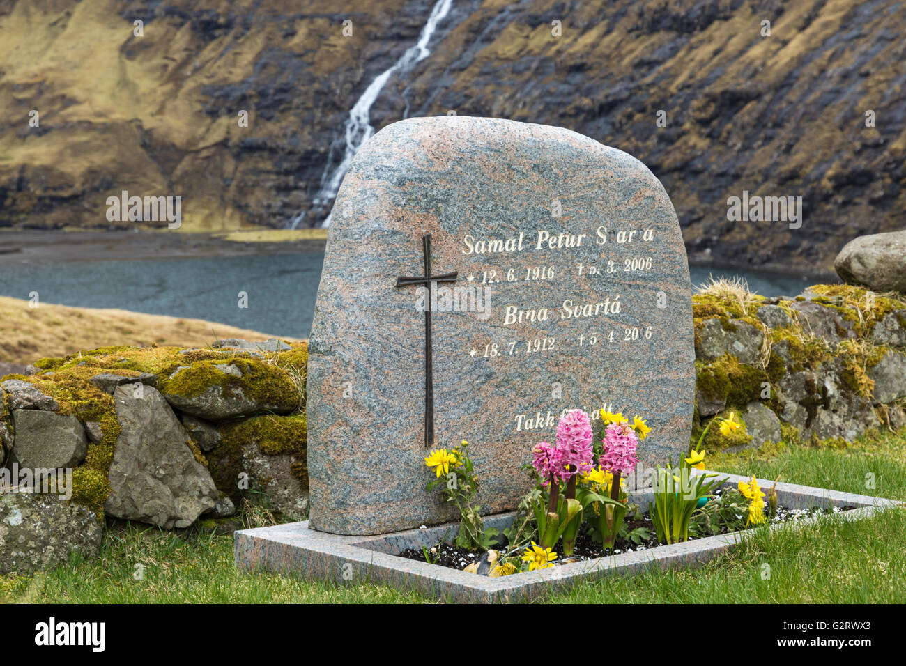 Headstone in church cemetery with waterfall at Saksun ancient village, Streymoy, Faroe Islands, Denmark in April Stock Photo