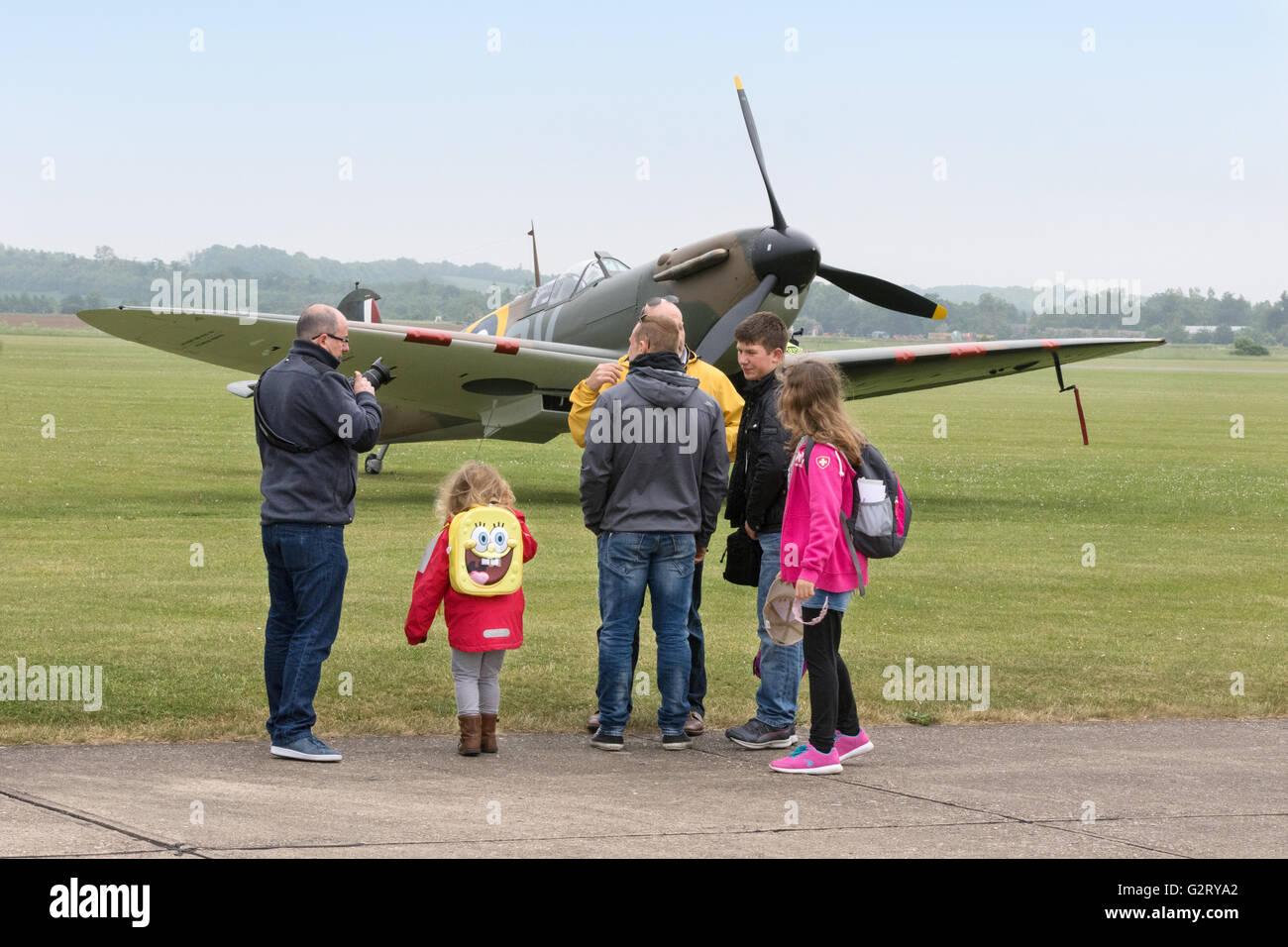 A family with children looking at a WW2 Spitfire plane at the Duxford Air Show, Imperial War Museum, Duxford IWM, Cambridgeshire UK Stock Photo