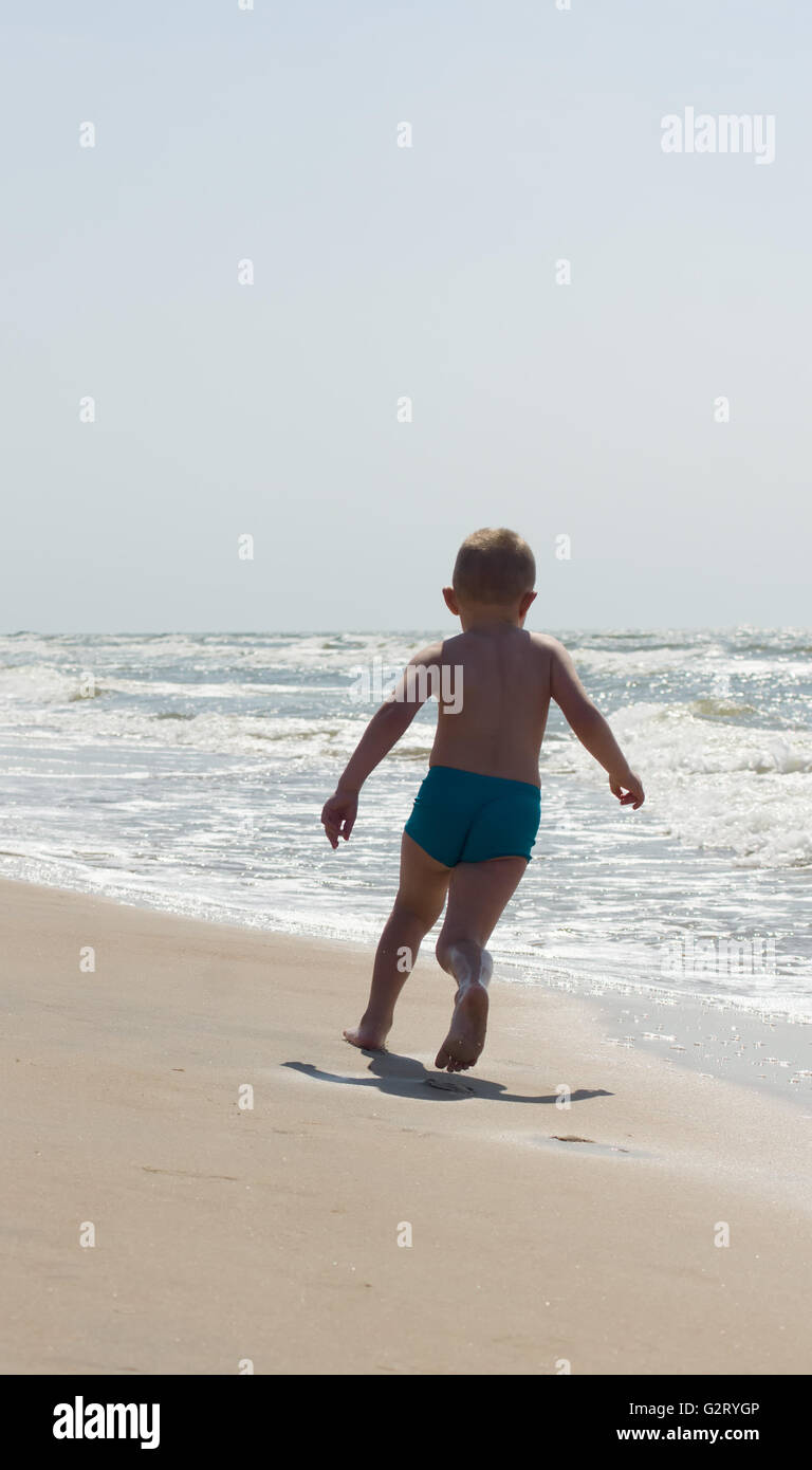 the little boy in blue swimming trunks has a good time at the sea Stock Photo