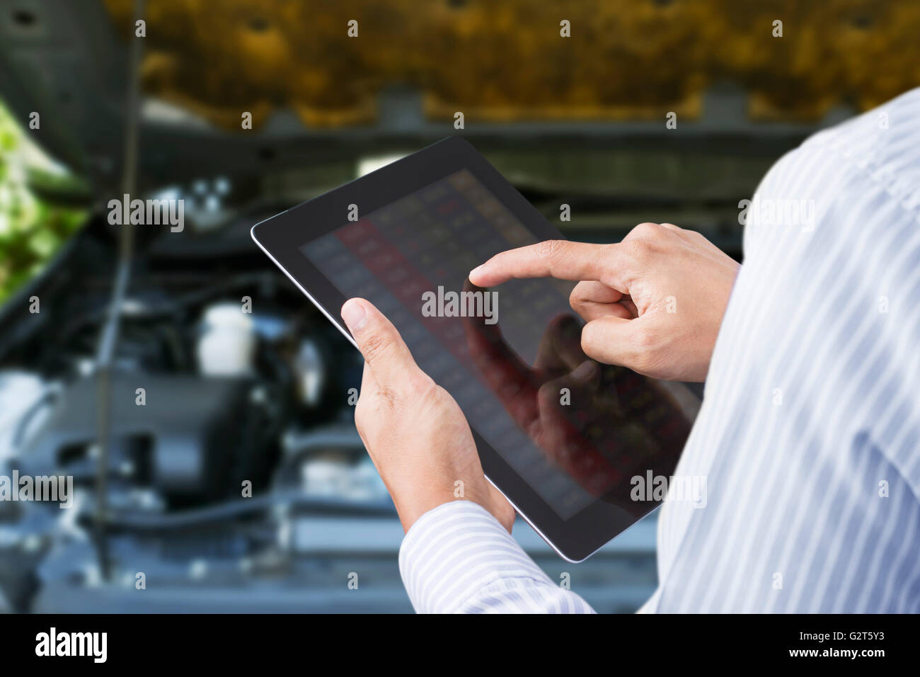 Closeup of a man checking the car on touchscreen tablet in a garage Stock Photo
