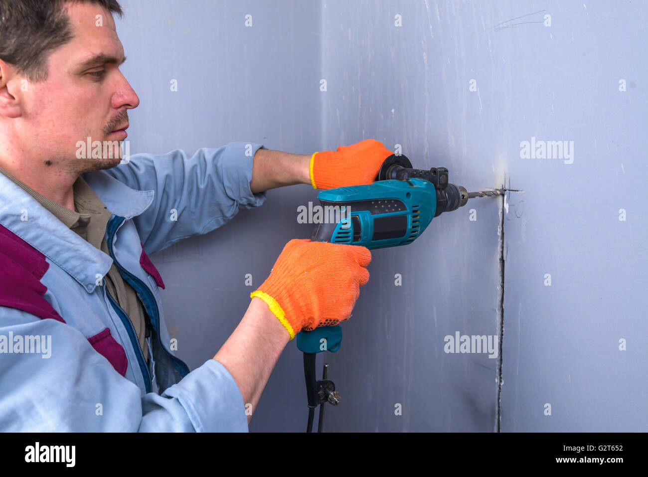 worker drills a wall in house Stock Photo