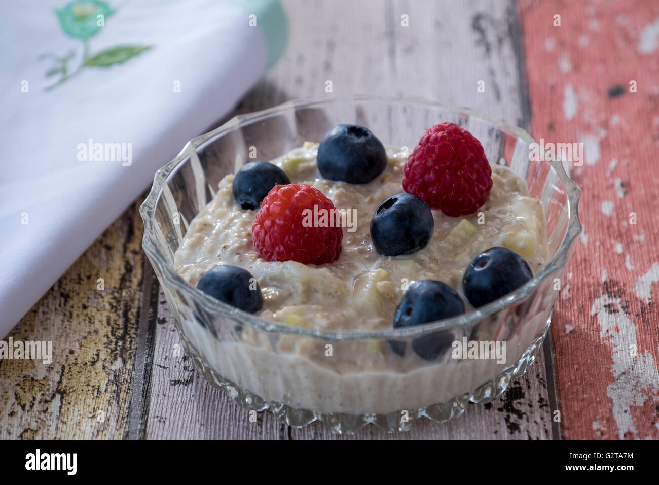 Homemade bircher muesli with summer fruits in glass dish with napkin on wooden background Stock Photo
