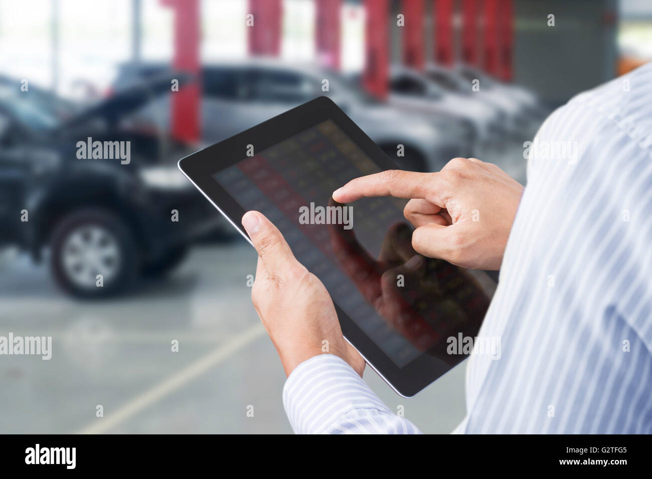 Closeup of a man checking the car on touchscreen tablet in a garage Stock Photo