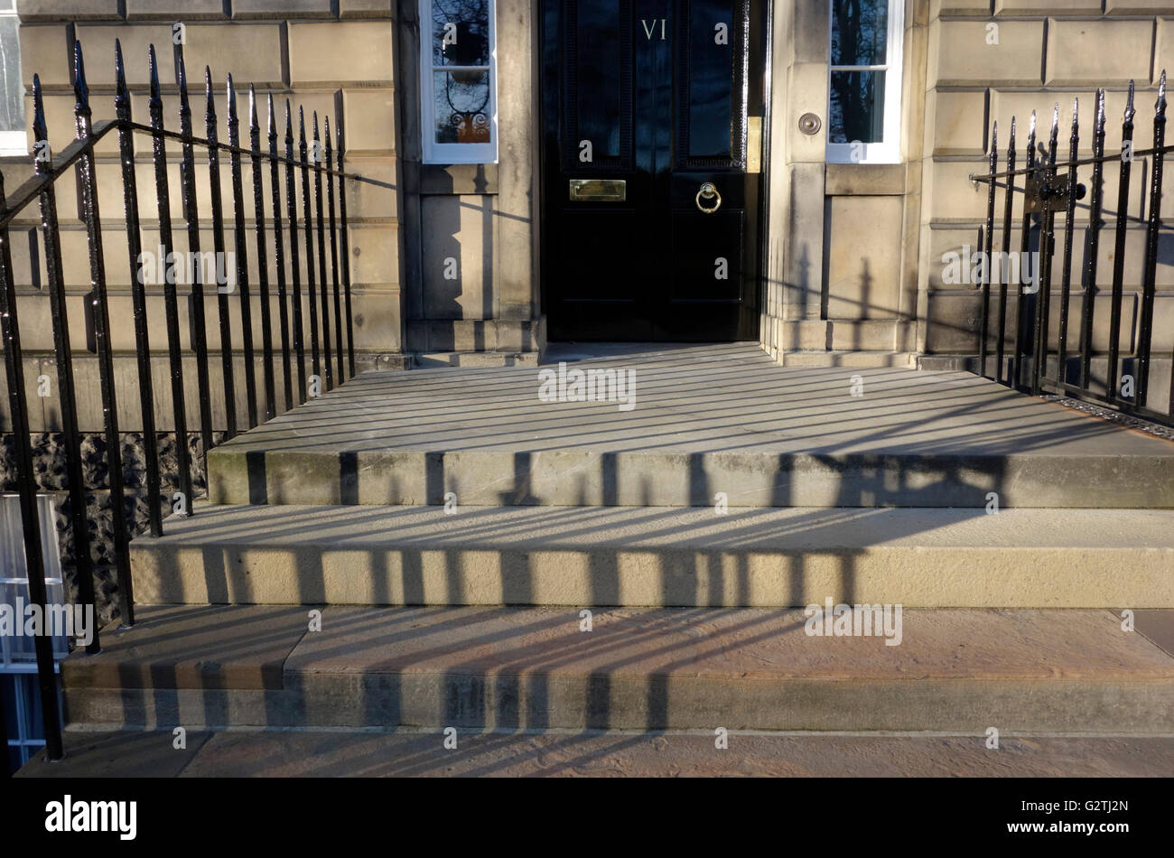 Shadows cast by iron railings at the entrance to a classical style