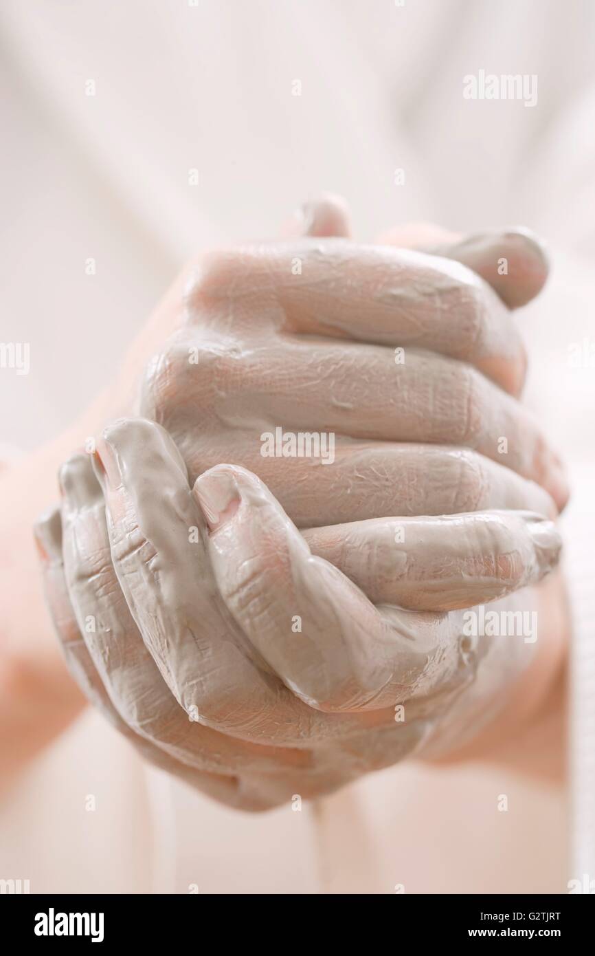 Young woman rubbing dark-coloured cream into her hands Stock Photo