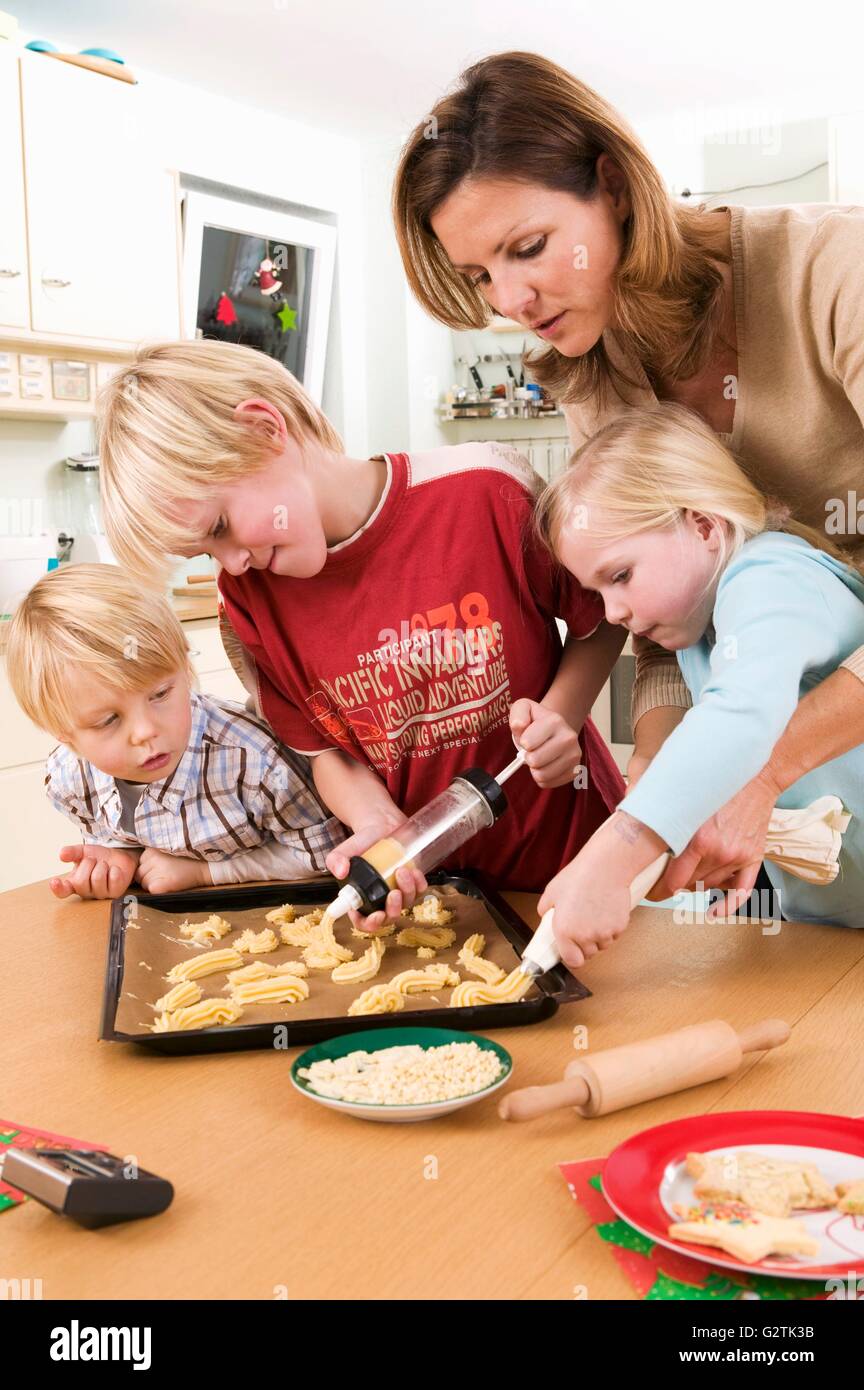 Mother and children making piped biscuits Stock Photo