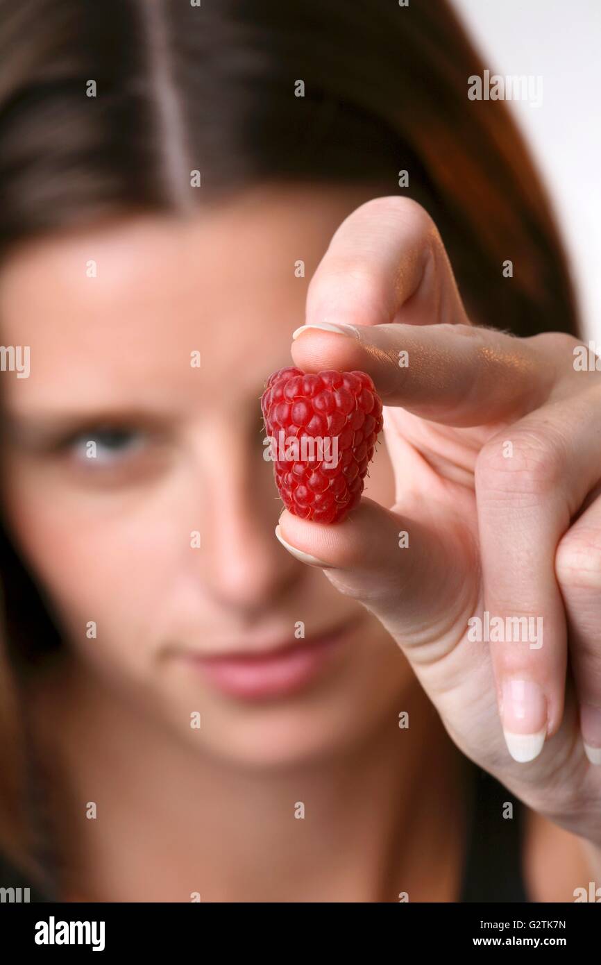 Young woman holding a raspberry Stock Photo - Alamy