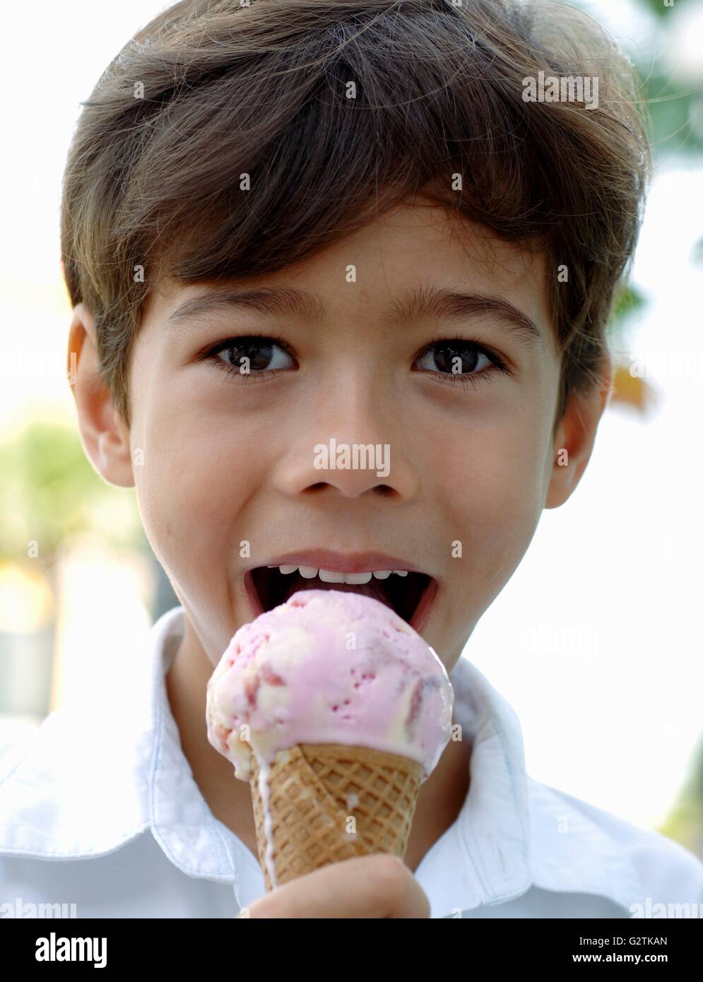 Boy eating strawberry and vanilla ice cream cone Stock Photo