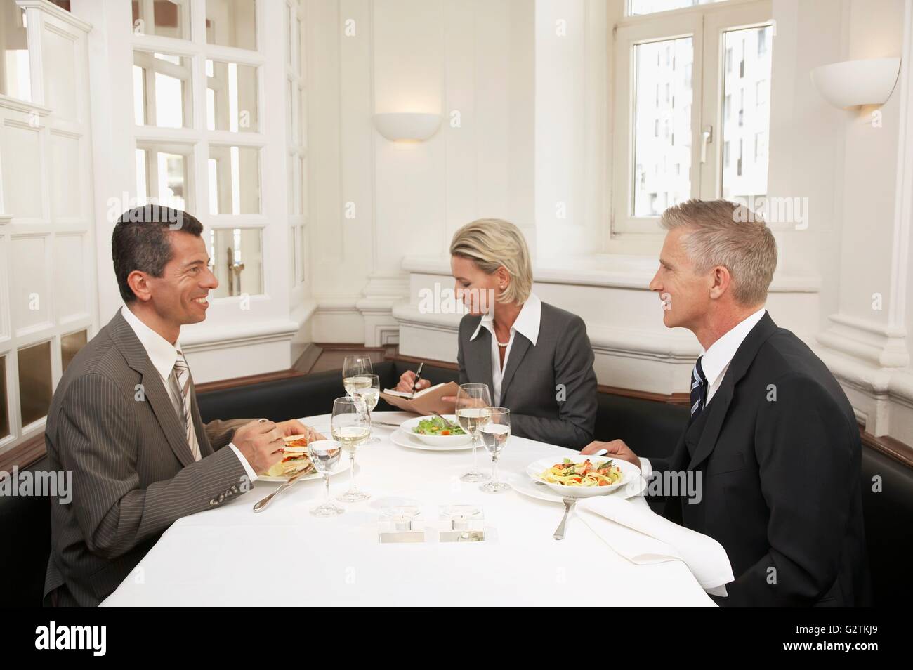 Woman between two men at a business meal Stock Photo