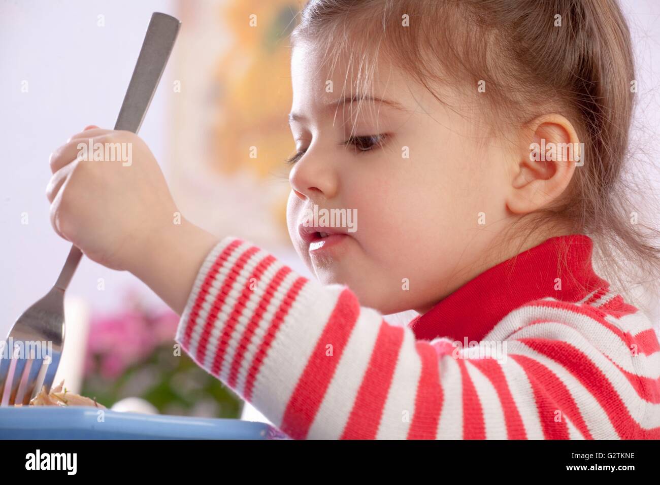 A little girl eating chicken Stock Photo