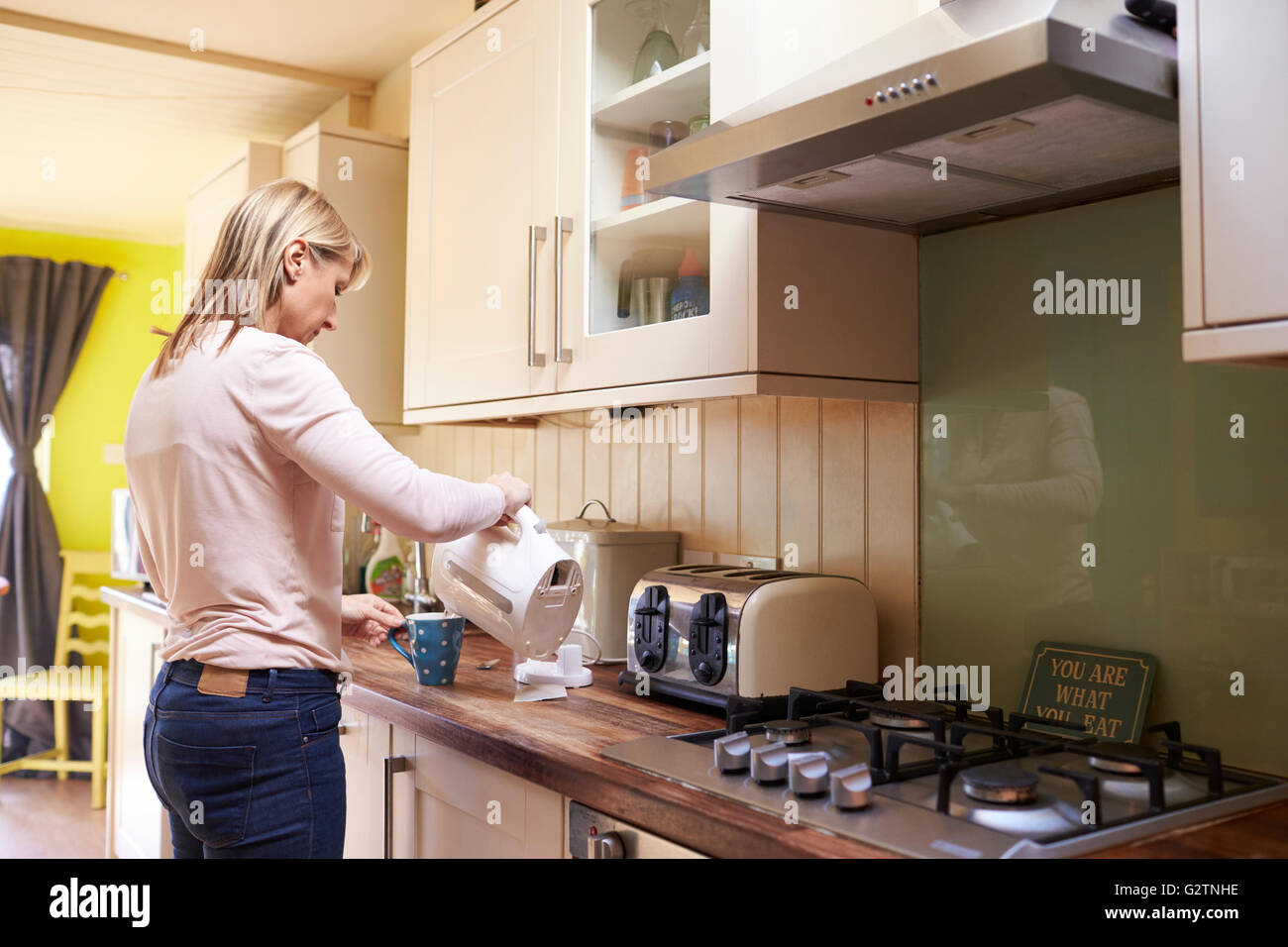 Woman Making Hot Drink In Kitchen Of Stylish Apartment Stock Photo