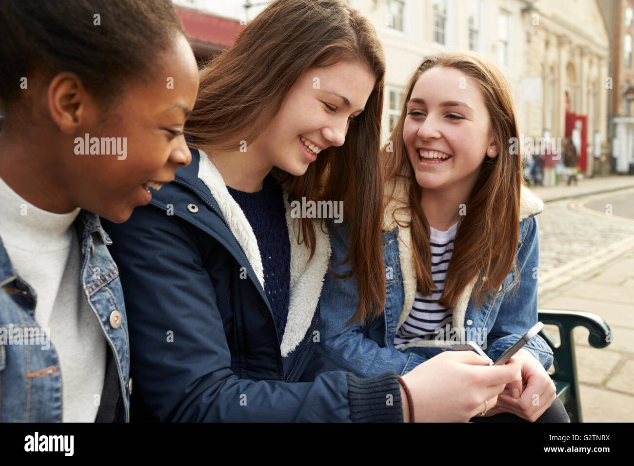 Teenage Girls Using Mobile Phones In Urban Setting Stock Photo