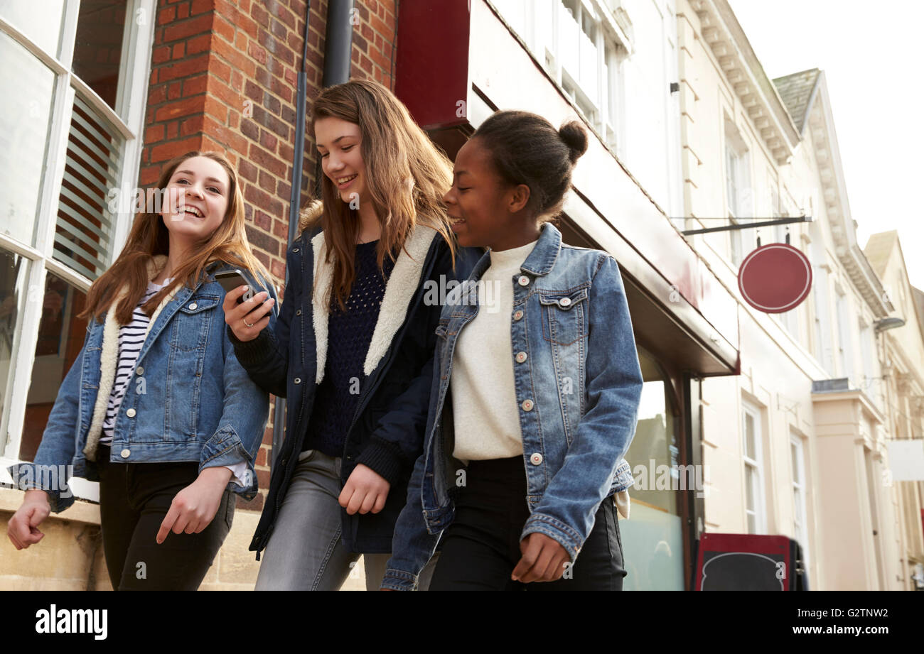 Teenage Girls Walking Along Street Looking At Social Media Stock Photo ...