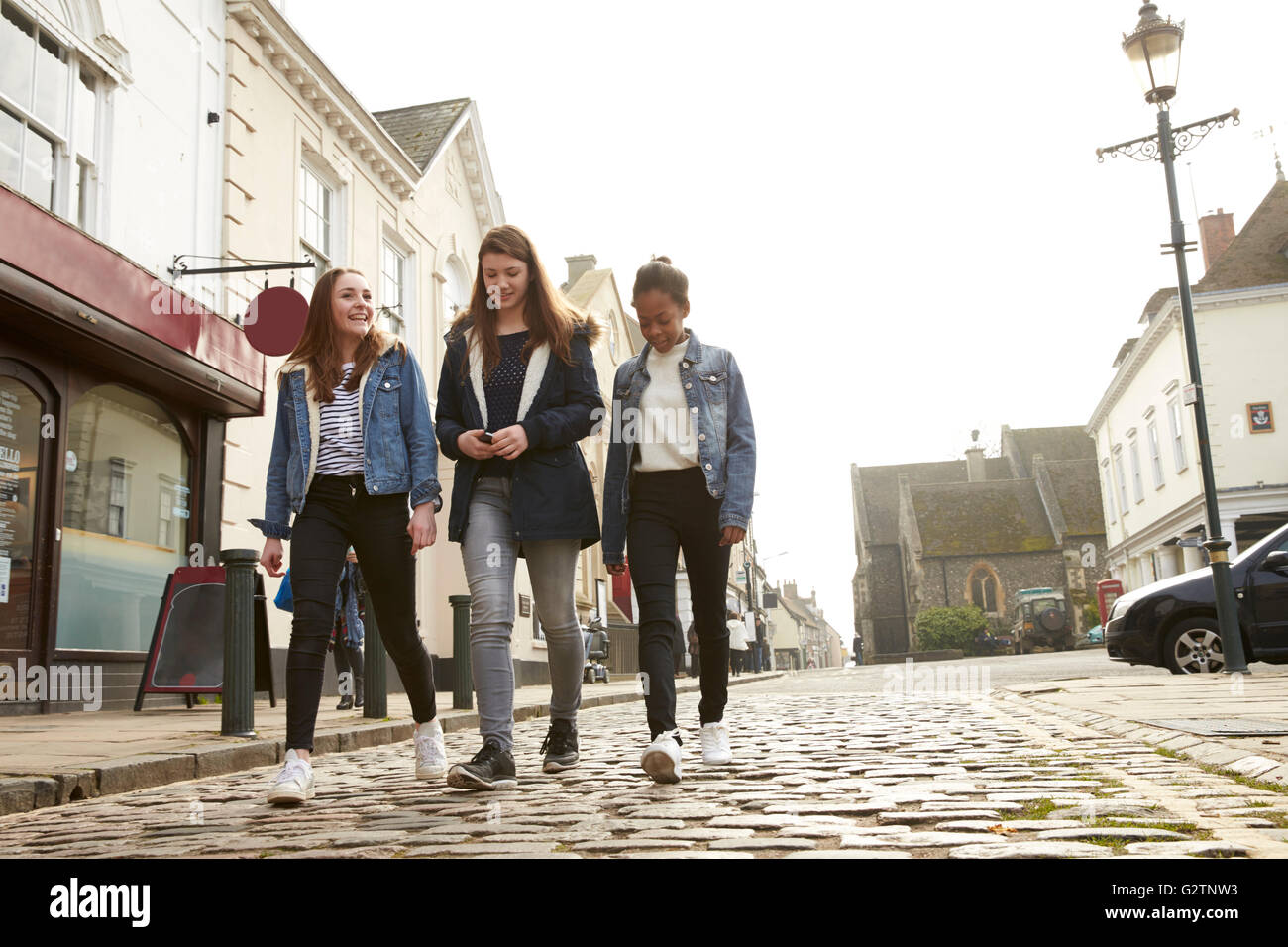 Group Of Teenage Girls Walking Along Urban Street Stock Photo