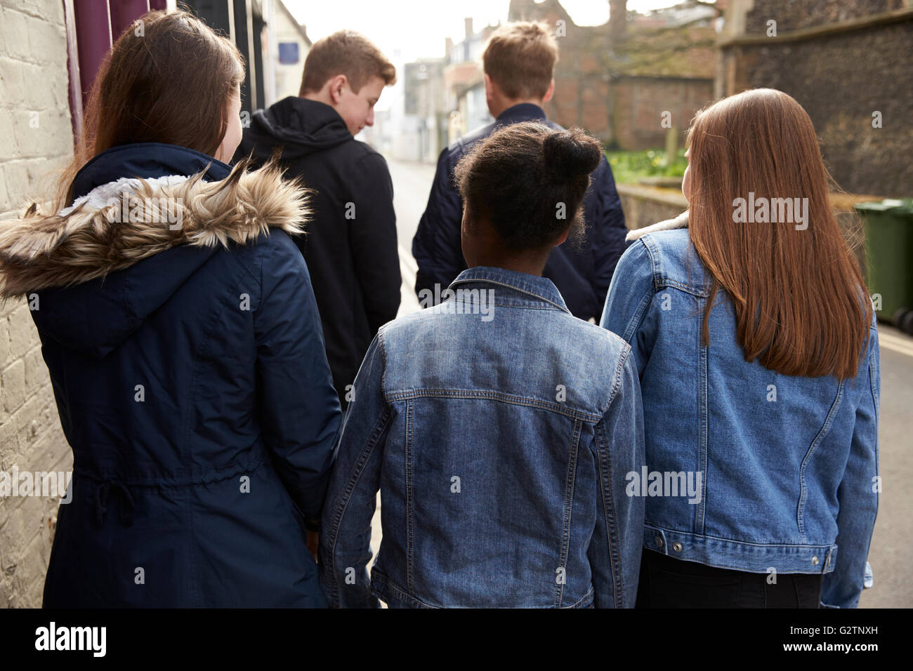 Rear View Of Teenagers Walking Along Urban Street Stock Photo