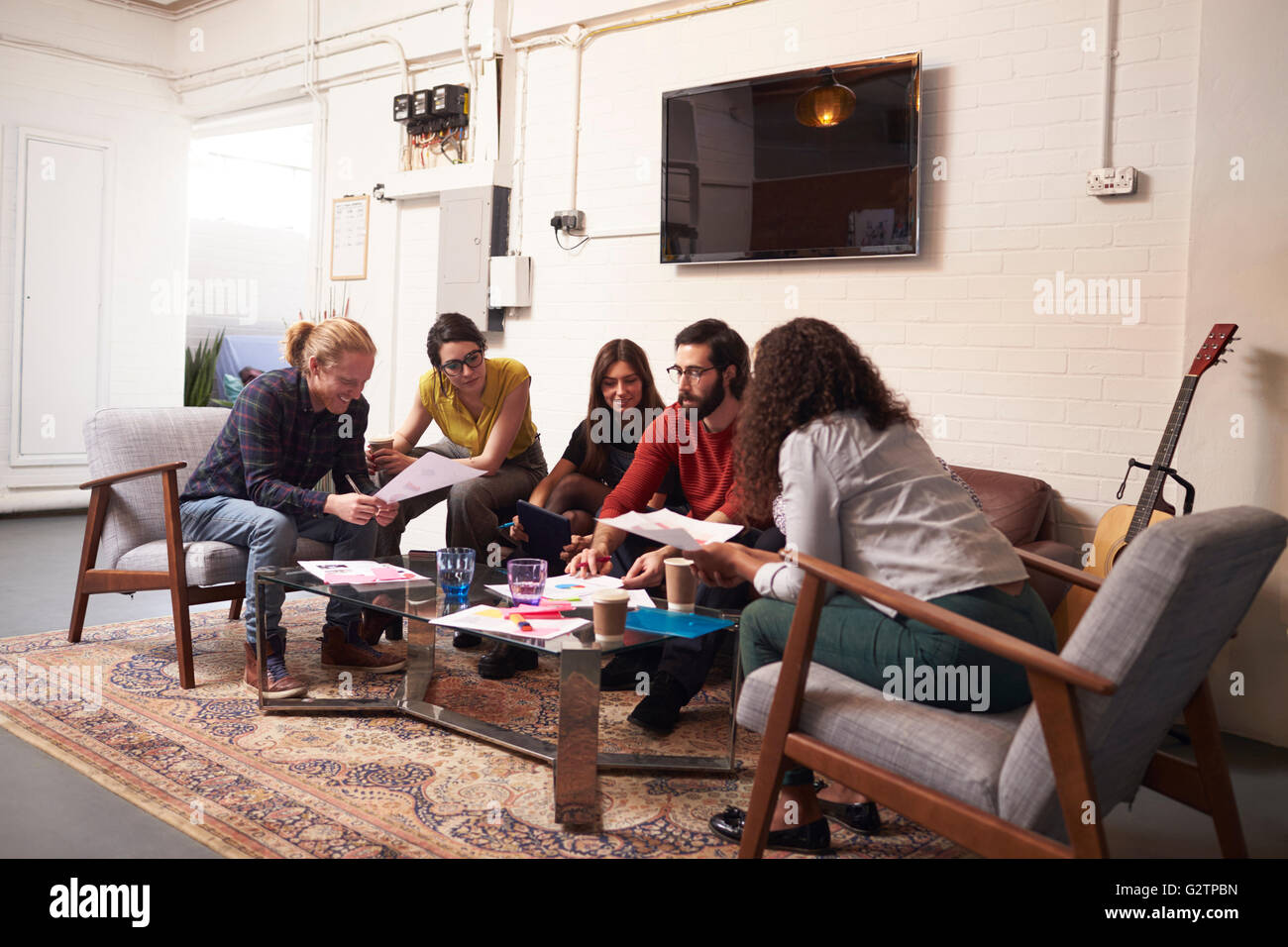 Designers Sitting On Sofa Having Creative Meeting In Office Stock Photo