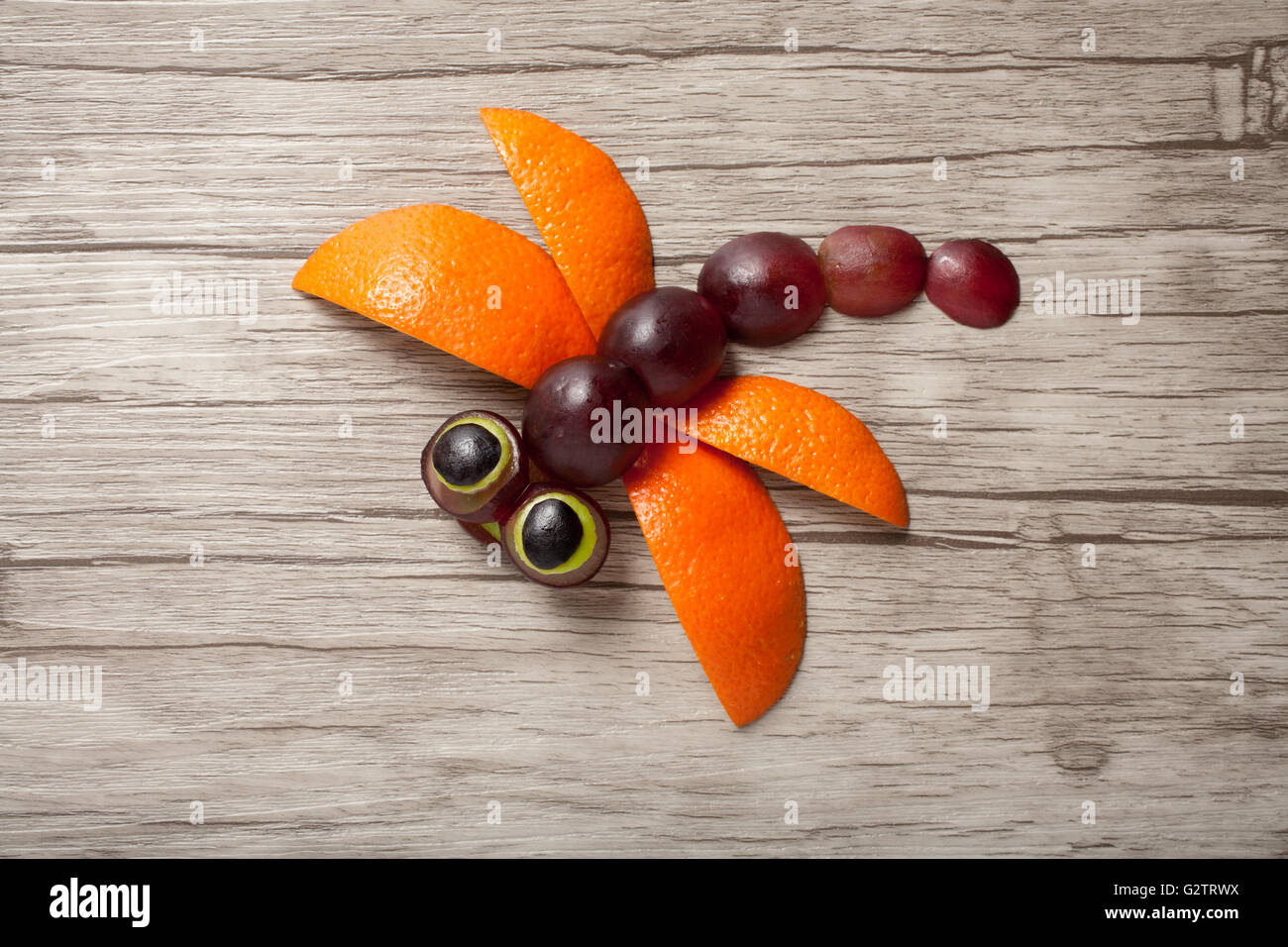 Funny dragonfly made of fruits on board Stock Photo