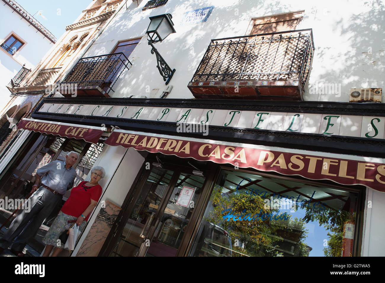 Spain, Andalucia, Granada, Elderly couple standing outside the Cafe Casa Pasteles on Plaza Larga in the Albayzin district. Stock Photo