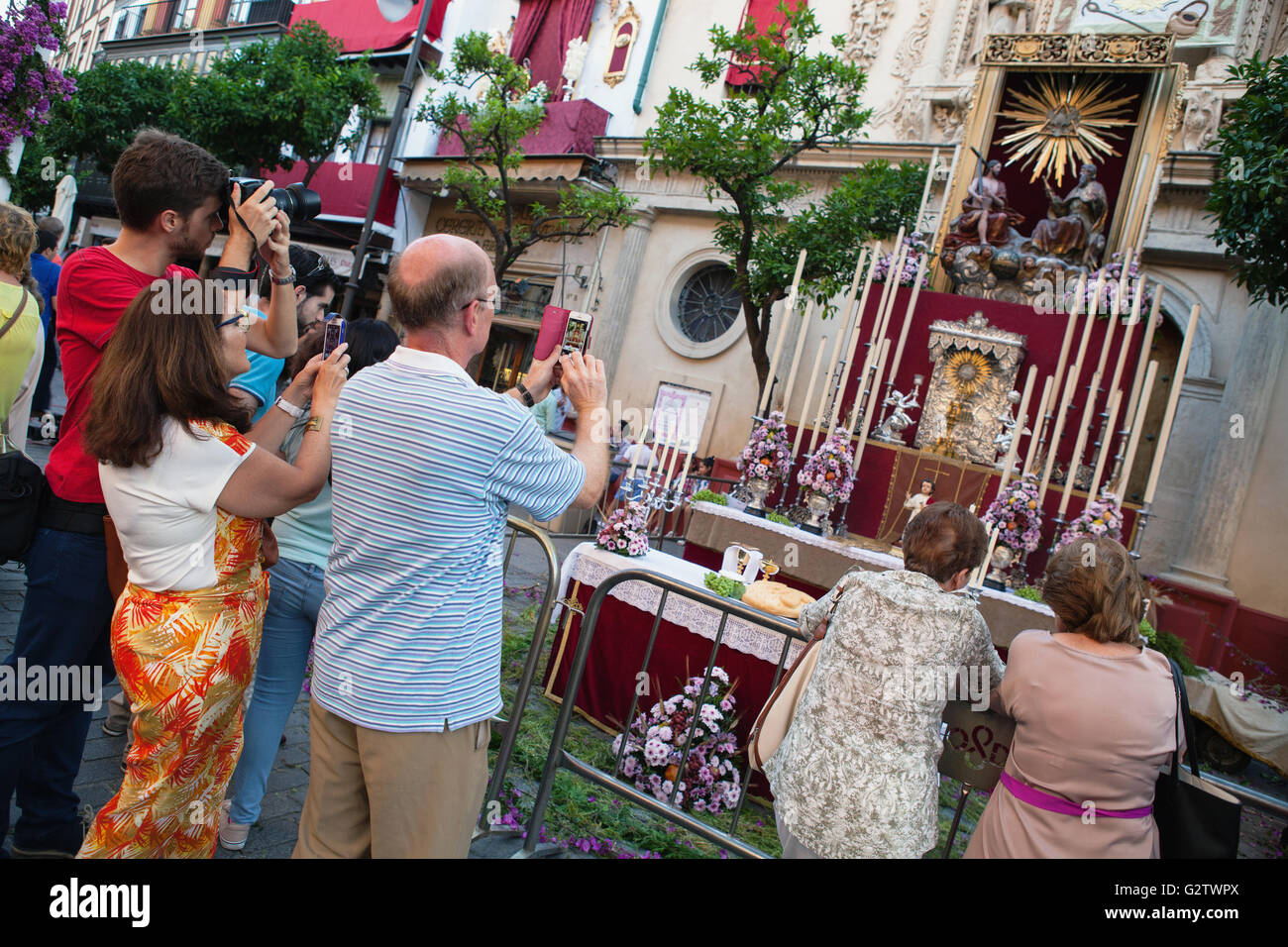 Spain, Andalucia, Seville, Worshippers take photographs of the temporary shrine in front of the Iglesia Colegial Divino Salvador that is on display to celebrate the feast of Corpus Christi. Stock Photo