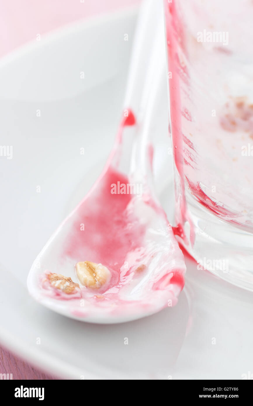 A dirty and used glass and spoon on a plate after dinner. Stock Photo
