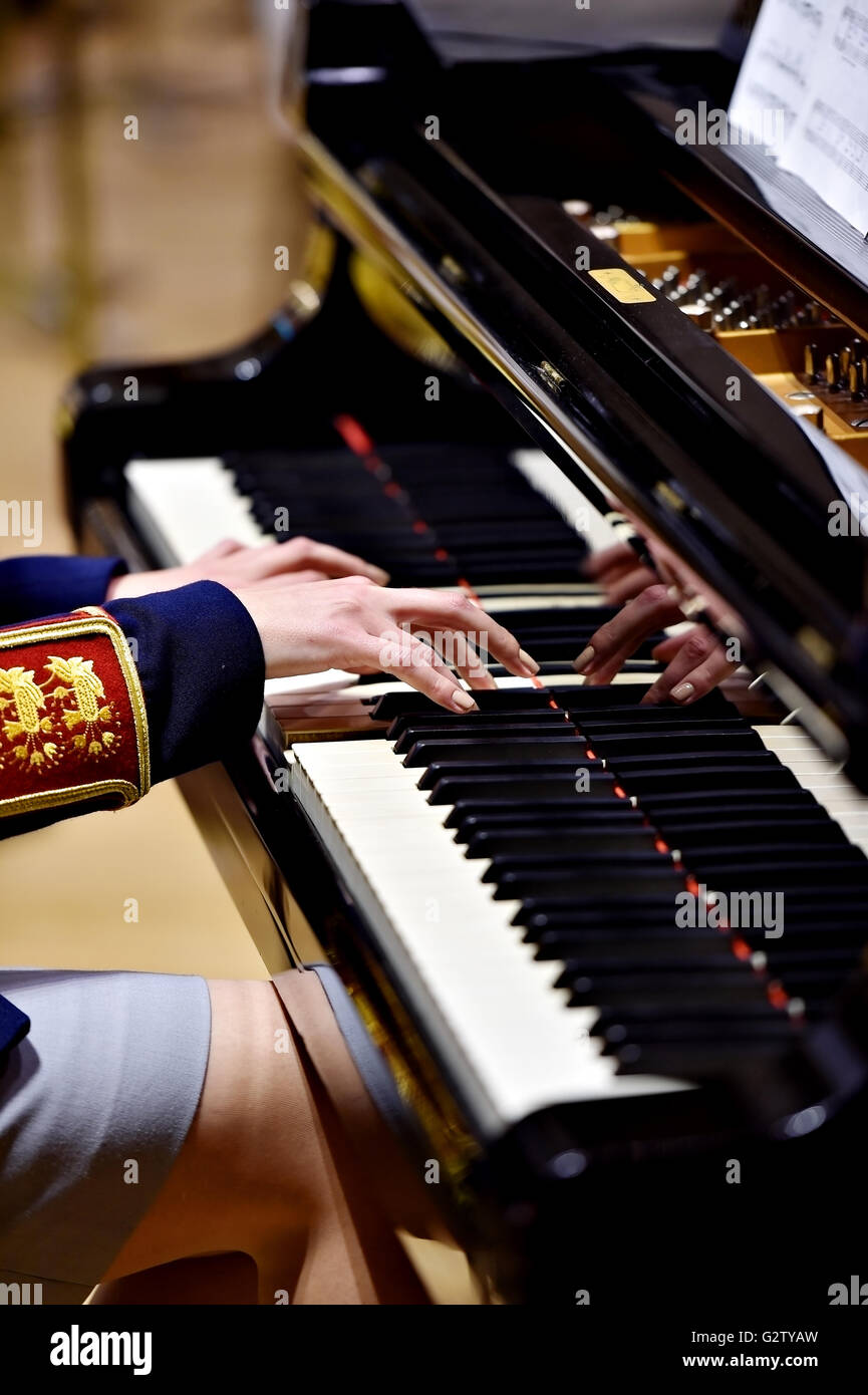 Hands of a woman part of a military orchestra performing at a piano during a concert Stock Photo