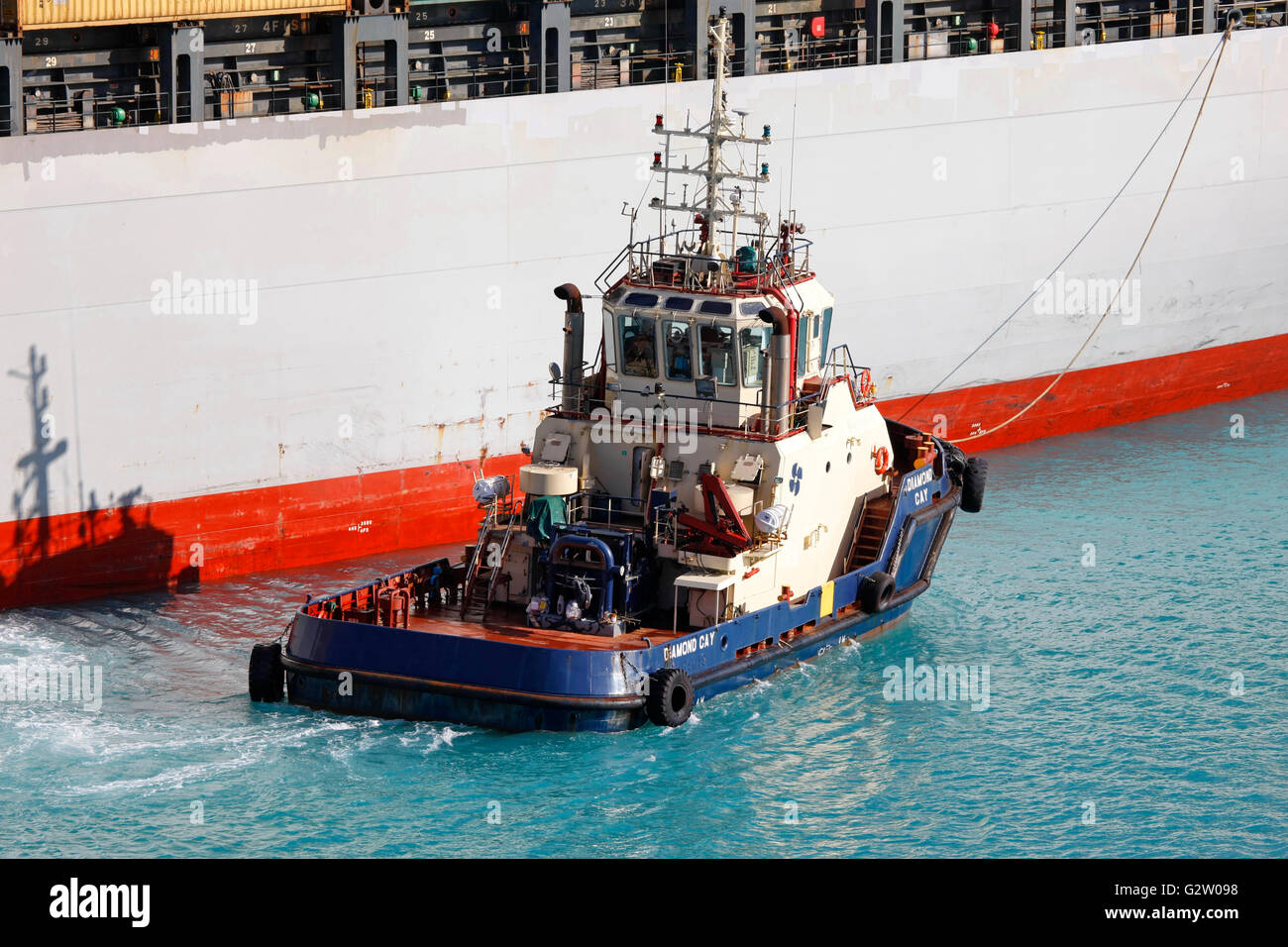 Tugboat pushing cargo ship in the port Stock Photo