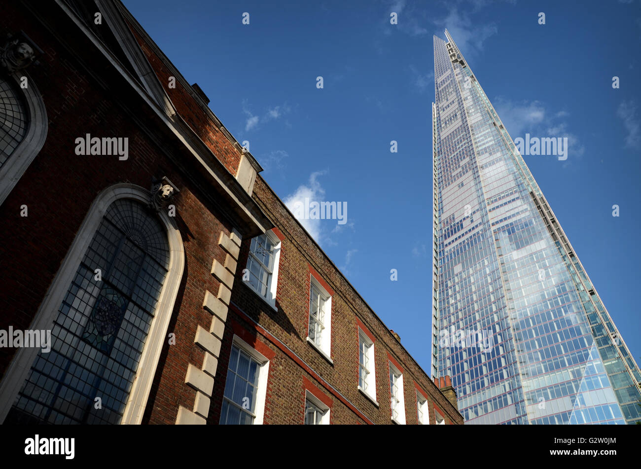 Contrast between old and new architecture in London, with the majestic Shard placed next to a quaint old brick building. Stock Photo