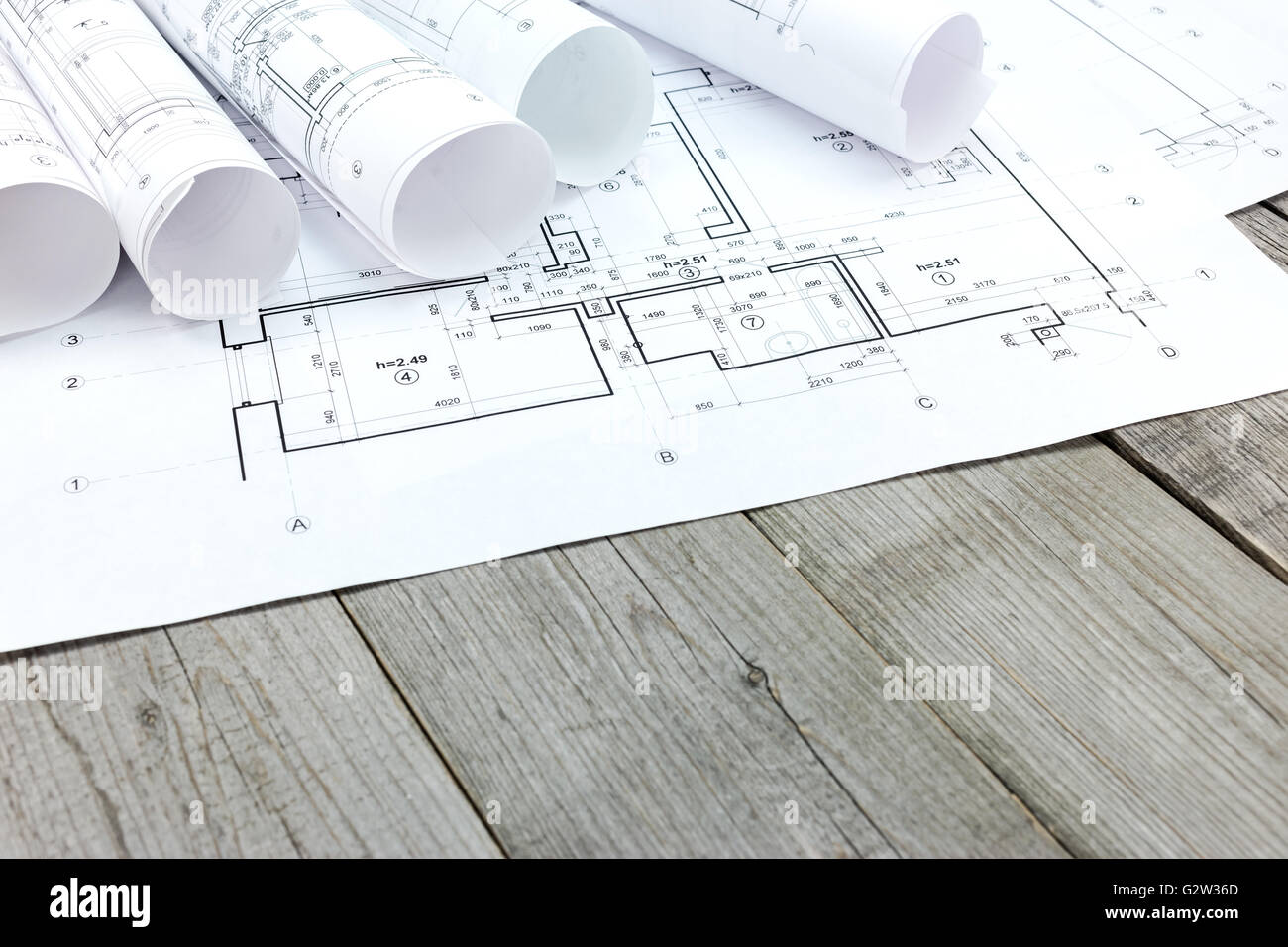 rolls of blueprints and architectural drawings on wooden desk Stock