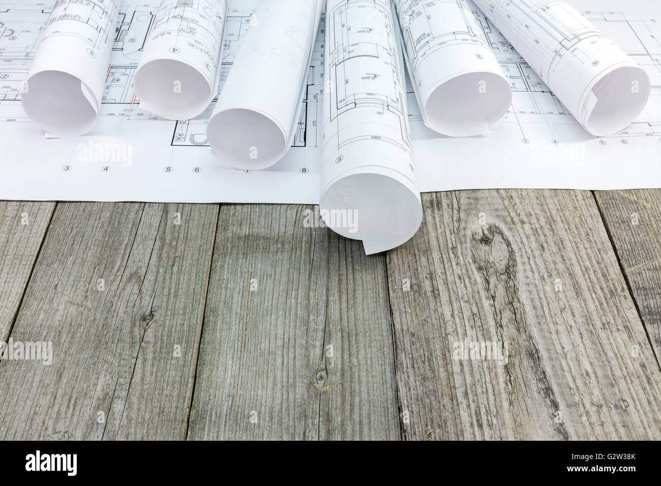 architectural blueprint rolls and floor plan drawing on gray wooden ...